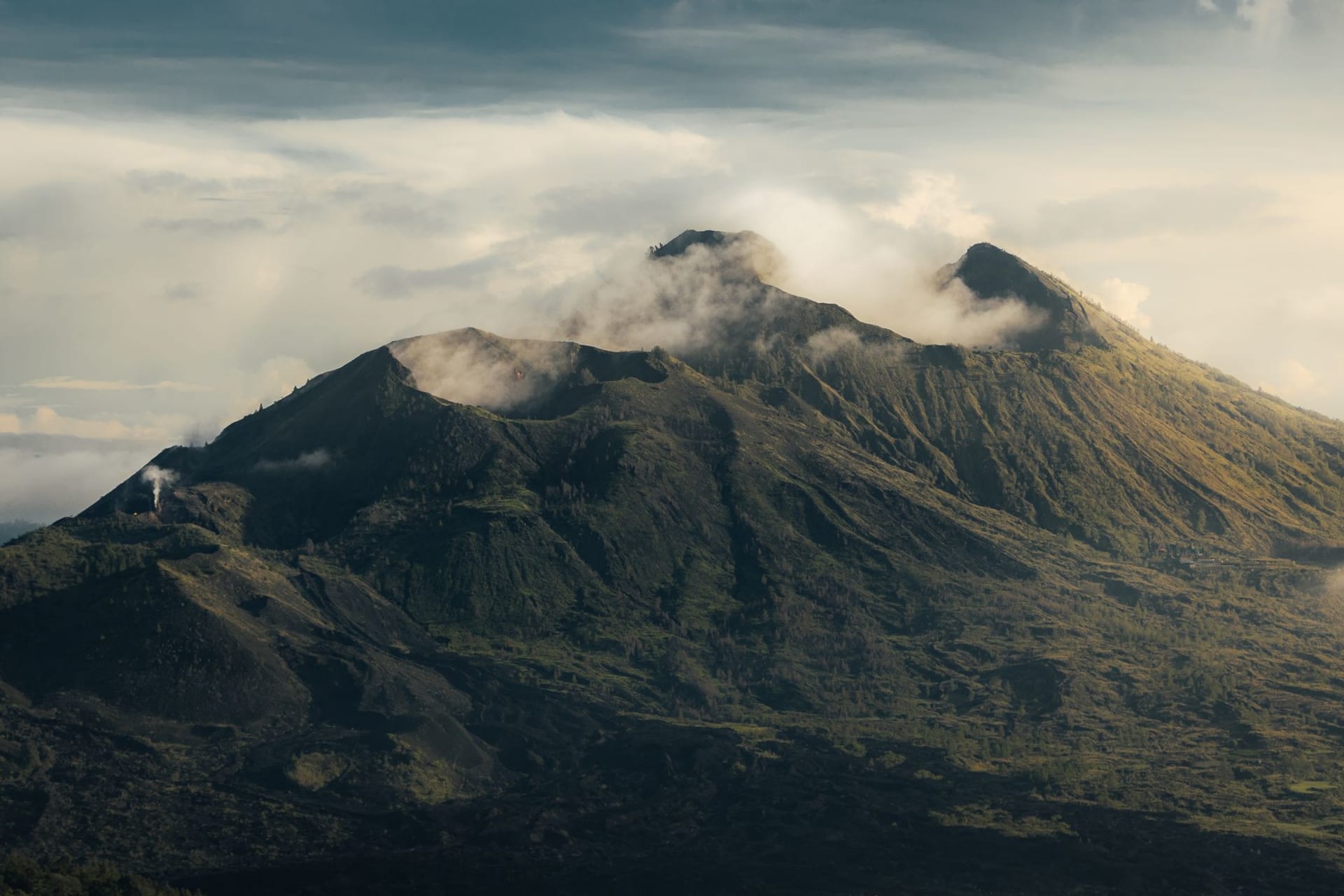 Sunrise from the summit of Mount Batur with Lake Batur gleaming below in the caldera and cloud layers spreading to the horizon