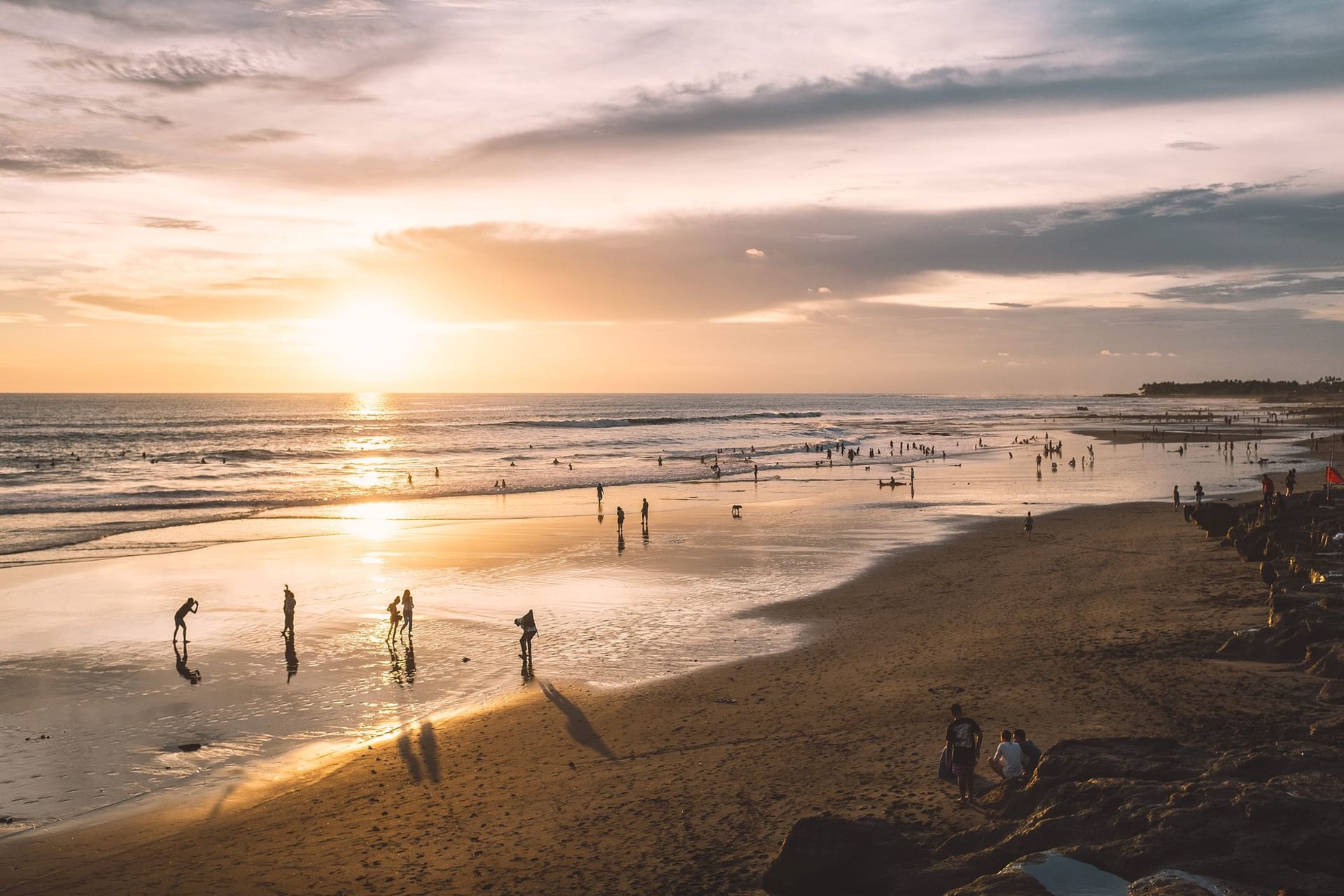 Seminyak beach at sunset with silhouetted beach club umbrellas and the sky burning orange over the Indian Ocean