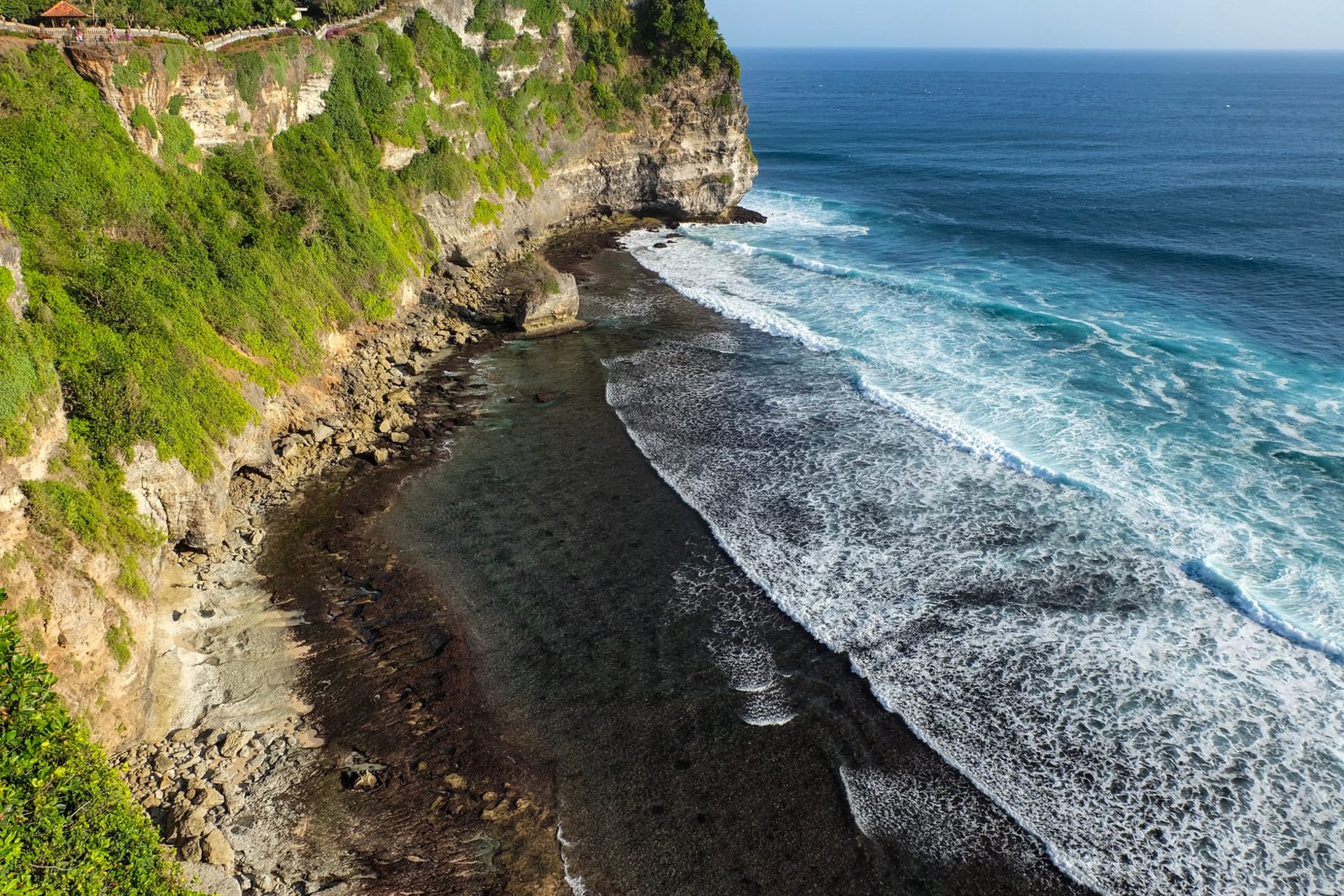Pura Luhur Uluwatu clifftop temple at sunset, limestone cliff face dropping to the Indian Ocean far below