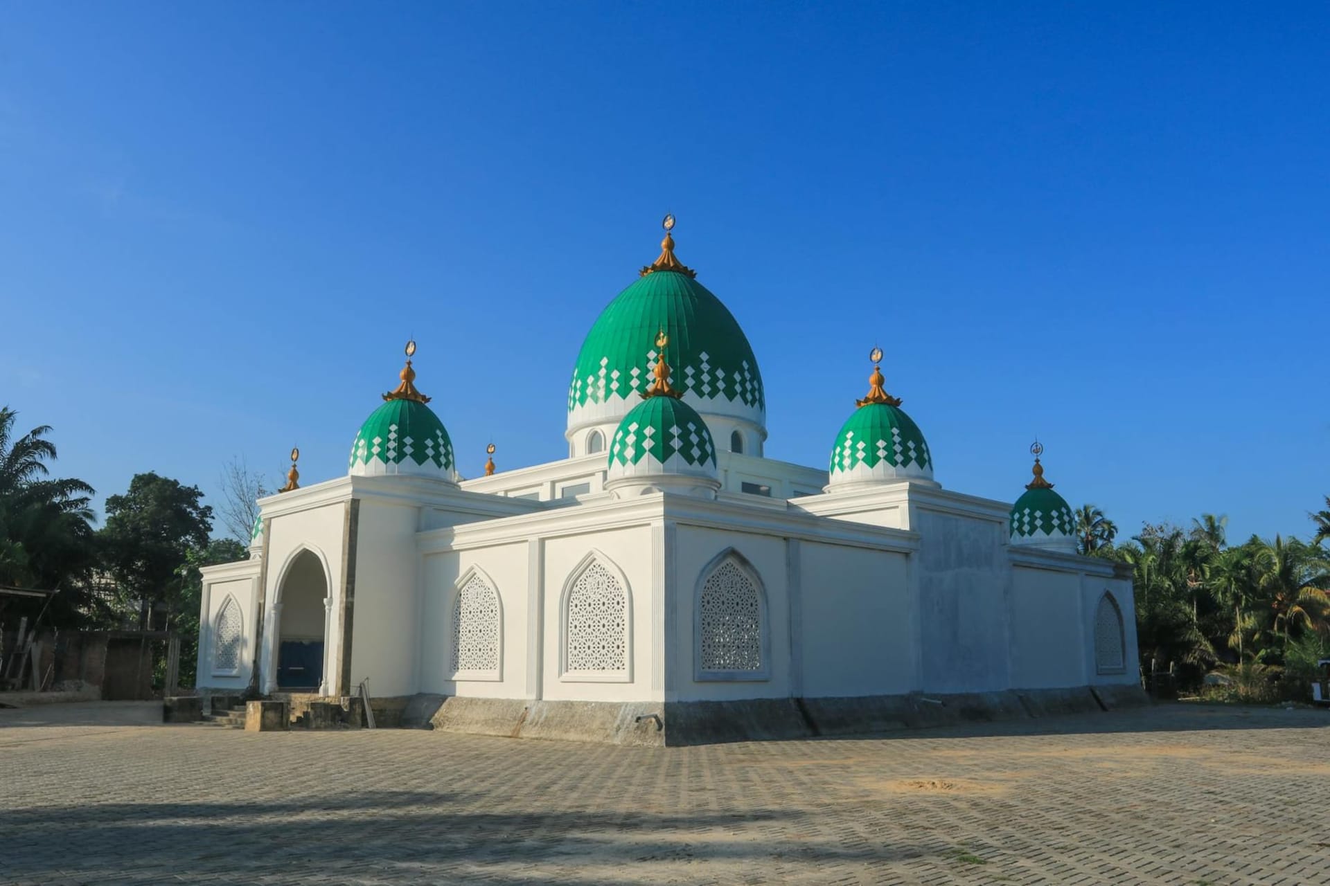 The honey-colored terracotta arches of the Sixty Dome Mosque rising from a green jungle clearing, late afternoon light casting long shadows across the carved stone pillars.