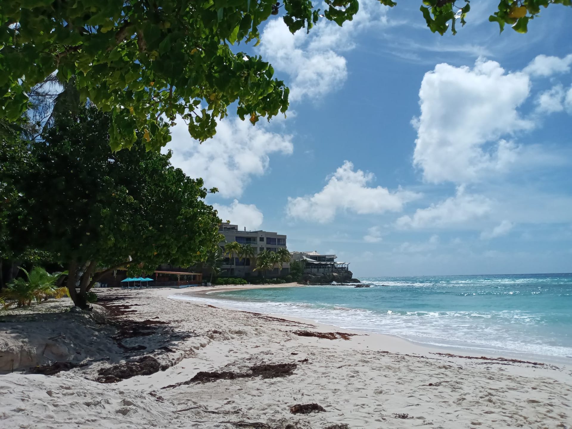 A calm turquoise bay near Bridgetown, Barbados, under a wide open sky with white sand stretching to the waterline — photo by Neil Marshall