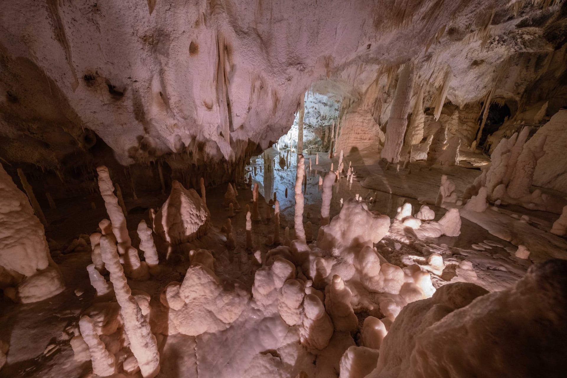 Massive stalactites and stalagmites illuminated in amber light inside Harrison's Cave, Barbados