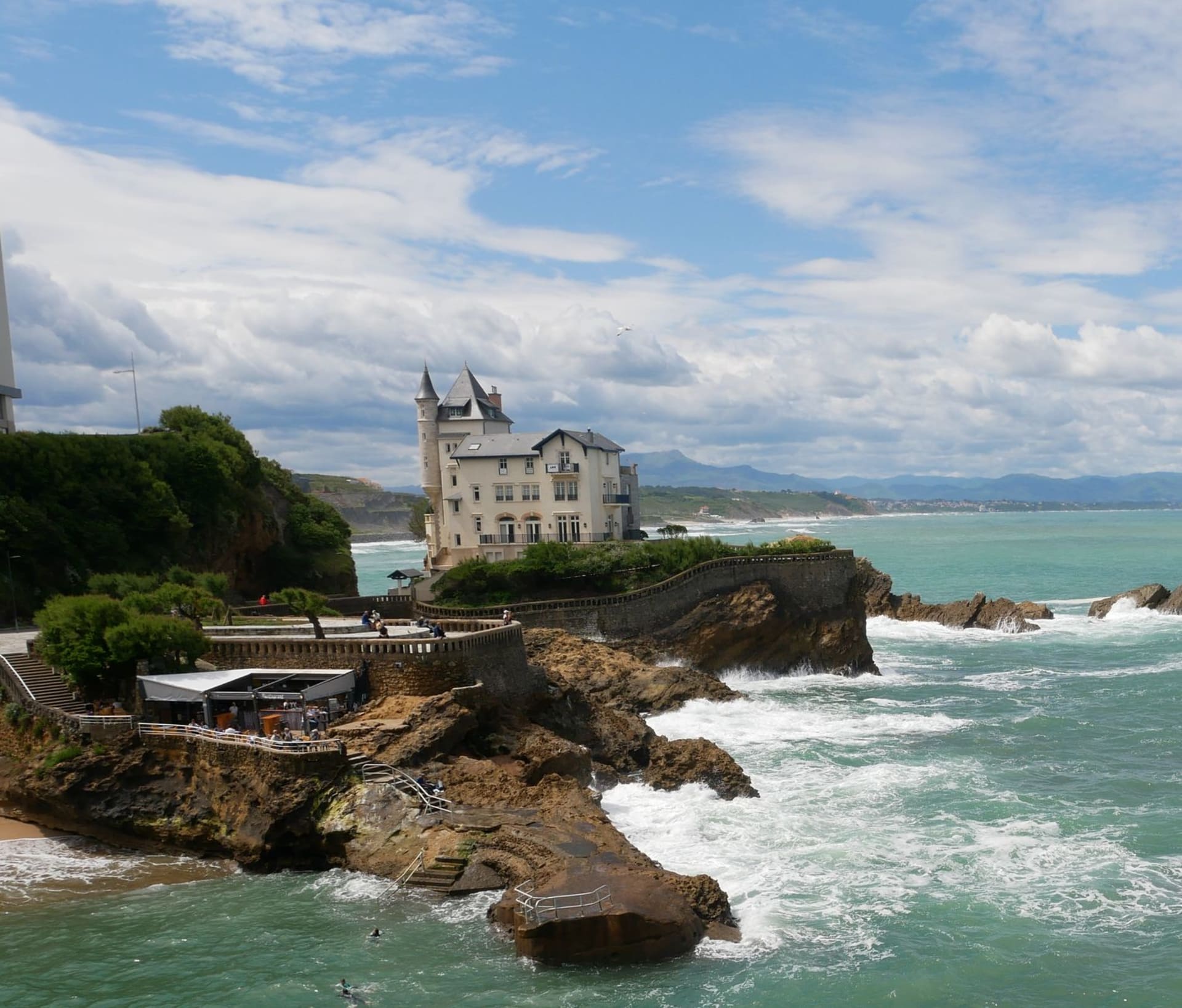 The Grande Plage of Biarritz at golden hour, the Art Deco casino on the cliff above and surf breaking below