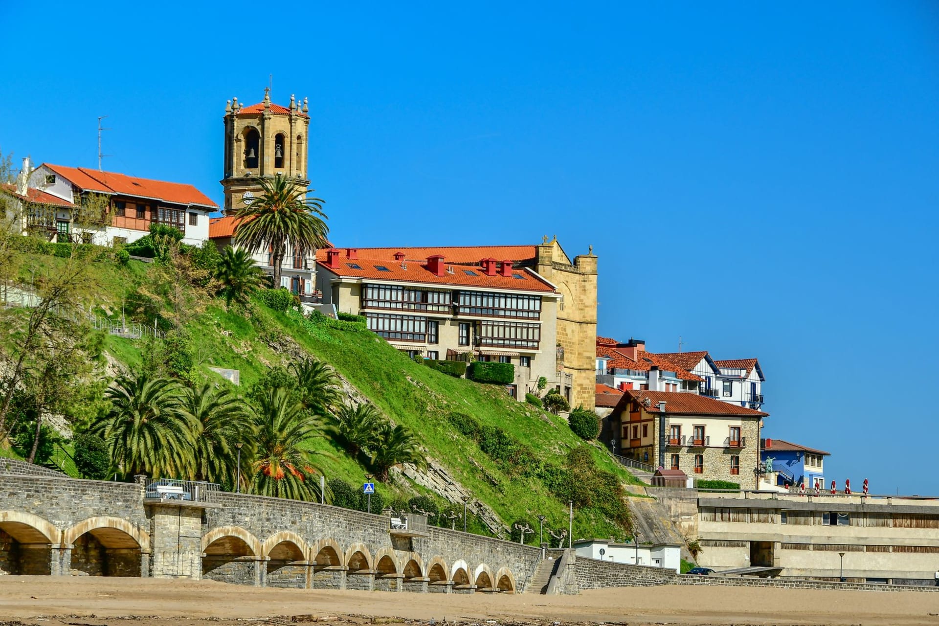 The medieval church of San Salvador leaning over the fishing port of Getaria, boats below and vine terraces rising behind