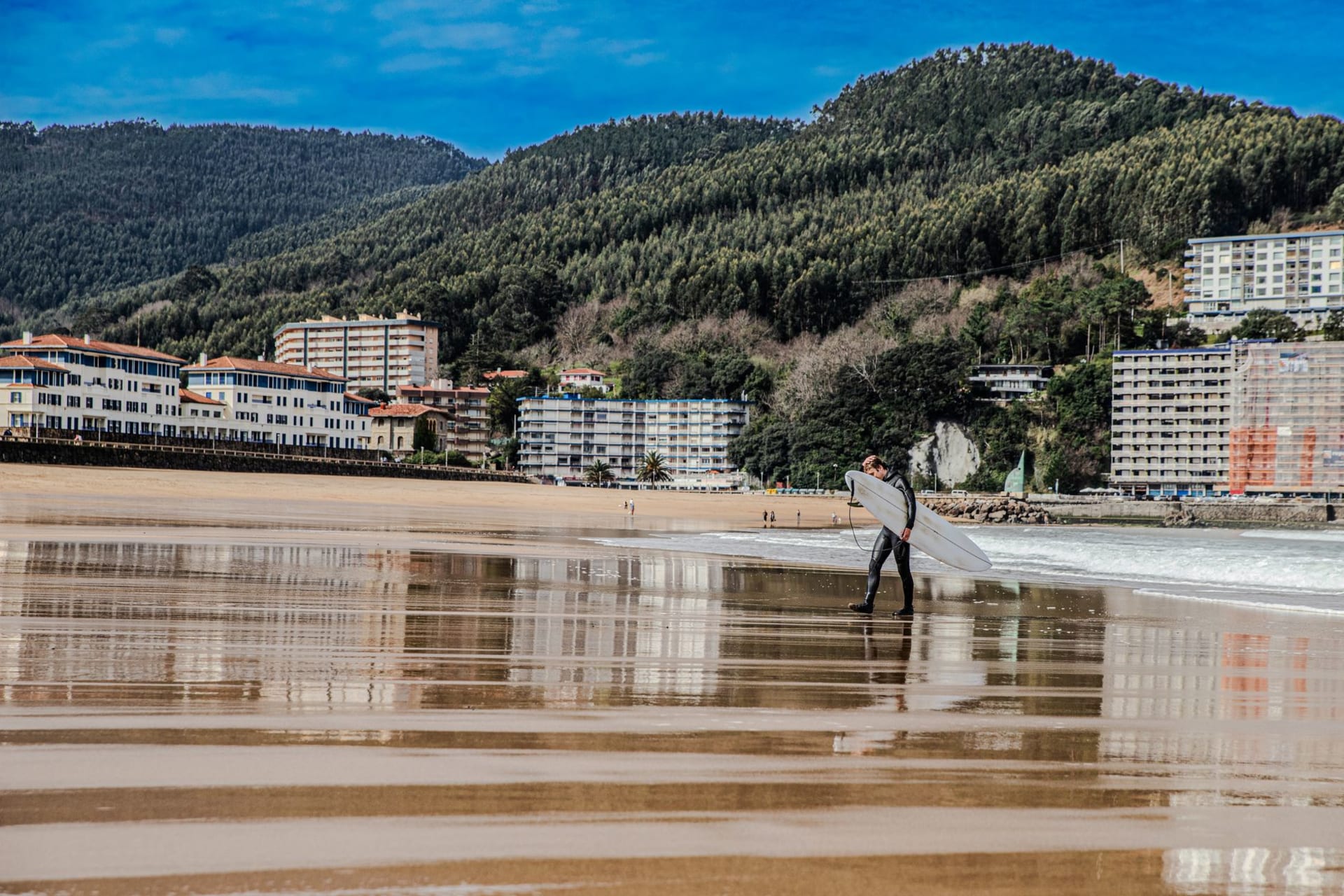 The long sandy beach of Zarautz lined with a promenade and green hills under a grey Atlantic sky