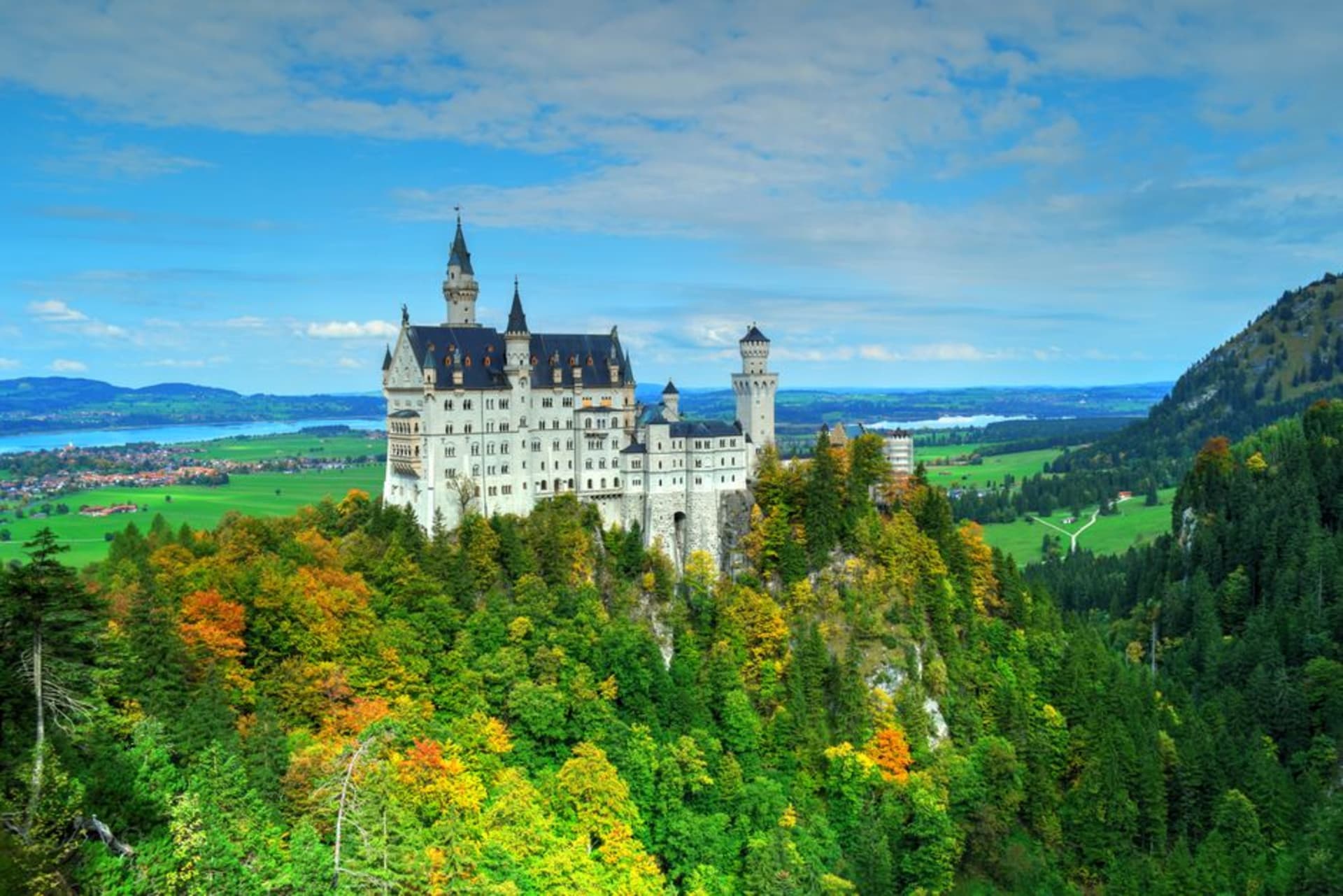Neuschwanstein Castle rising above the Bavarian Alps forest at golden hour