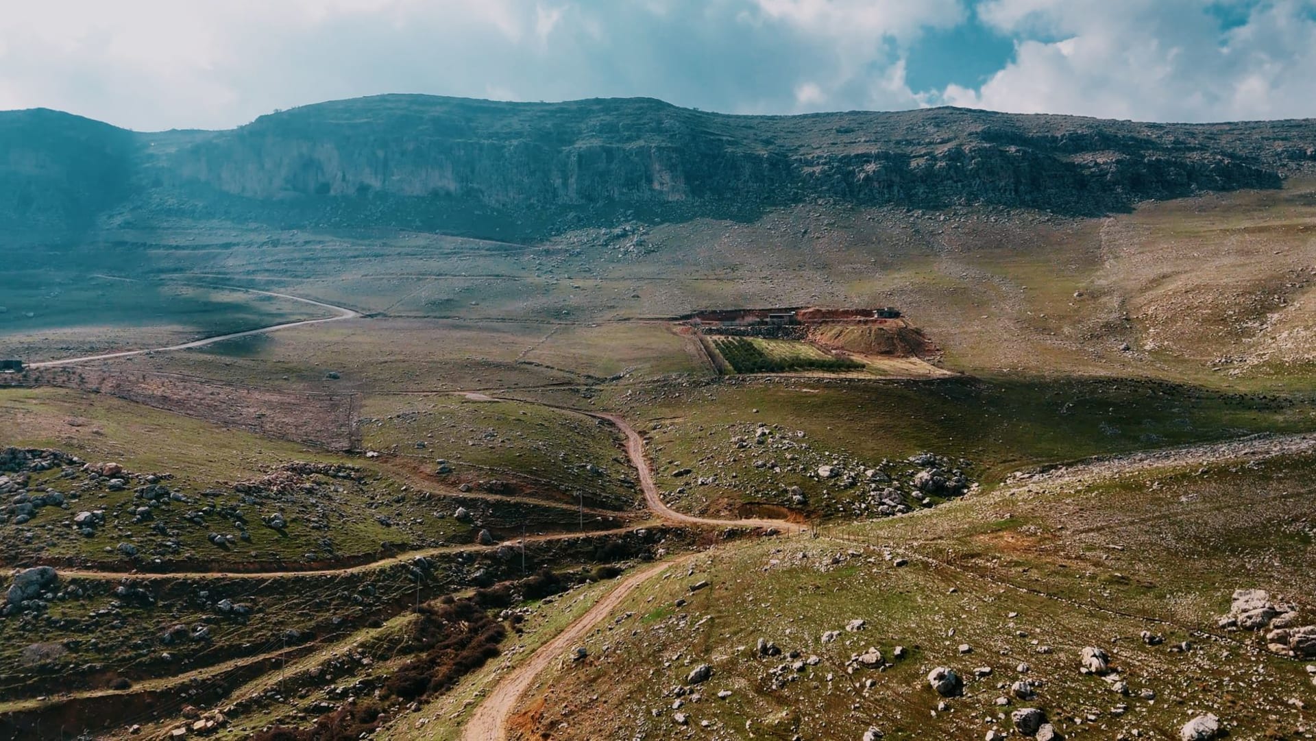 Traditional red limestone houses of Deir el-Ahmar clustered on a hillside, with the Bekaa Valley plain visible below