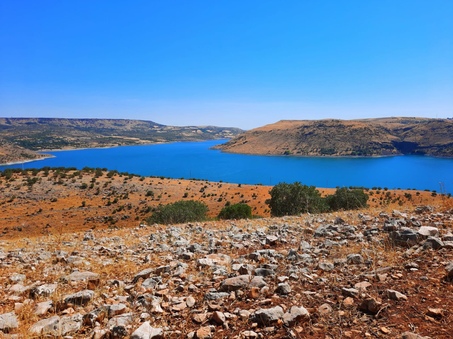 The still blue expanse of Lake Qaraoun reflecting the mountains of the southern Bekaa Valley under a wide sky