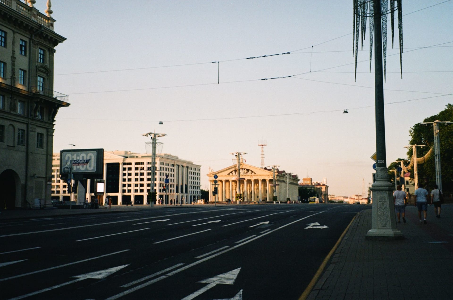 The golden-lit socialist-realist façades of Prospekt Nezavisimosti reflected in the Svislach River at dusk, Soviet lampposts framing the boulevard