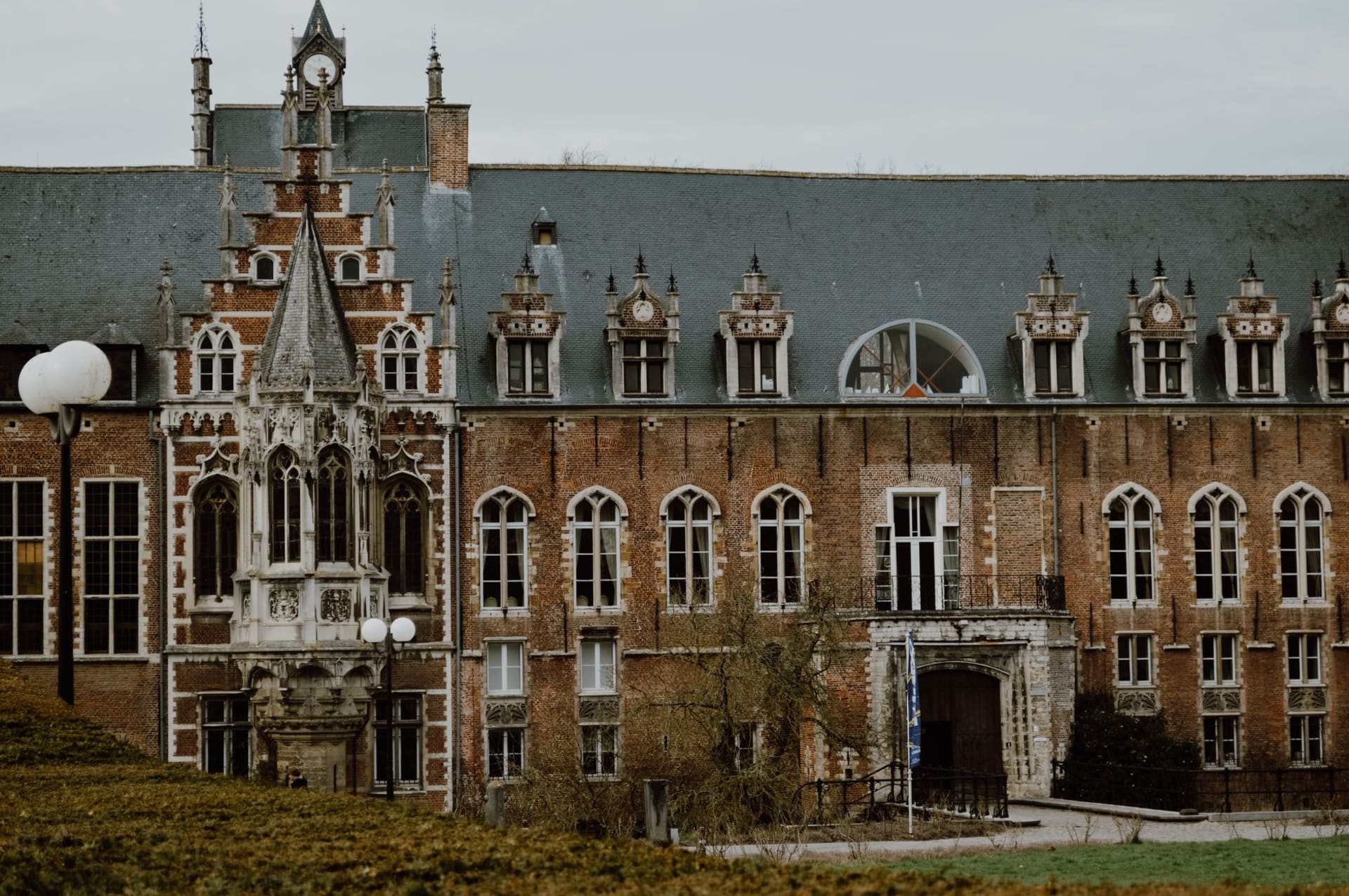The intricately carved Gothic facade of Leuven's town hall rising above the Grote Markt at golden hour, its hundreds of statues and pinnacles catching warm light