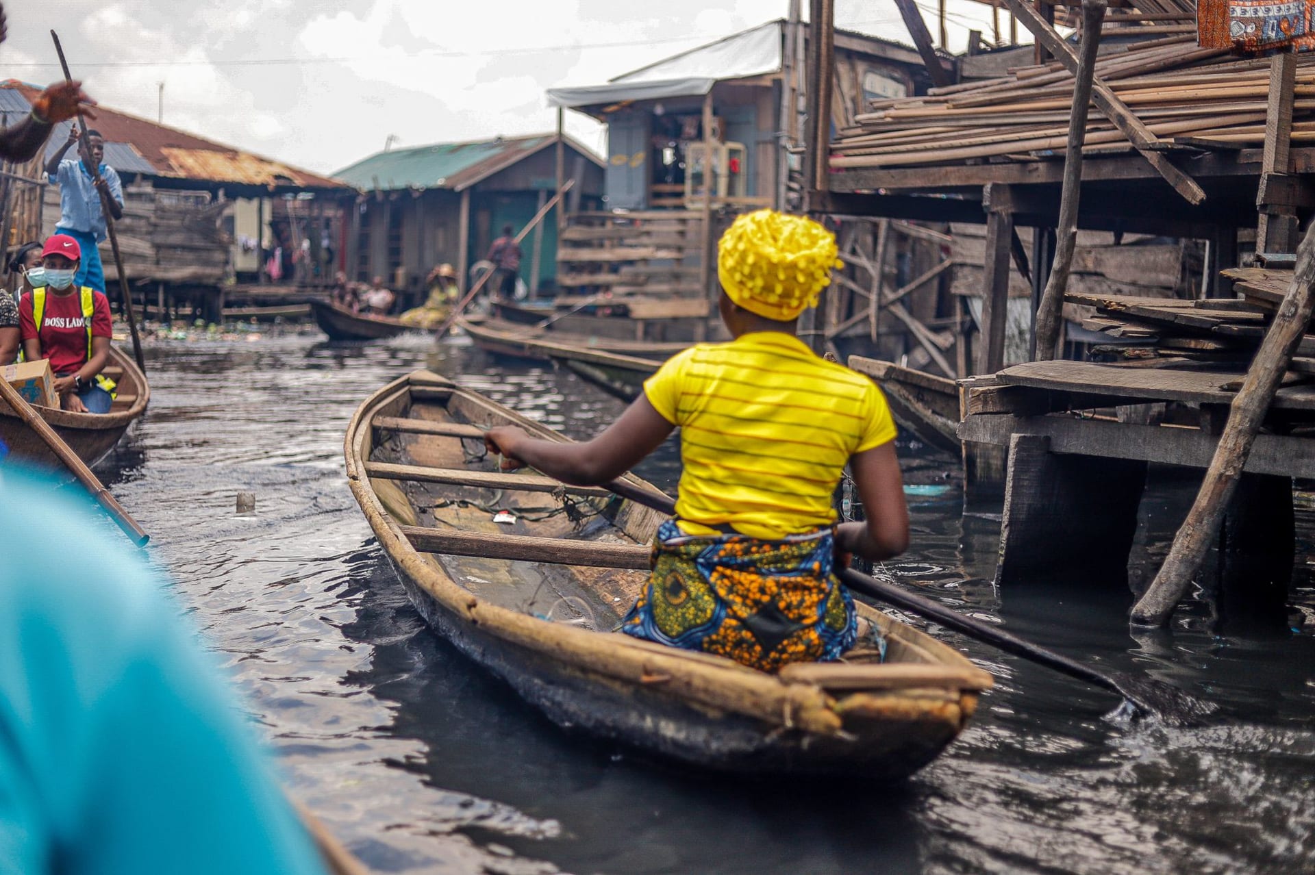 Wooden stilt houses rising from the brown waters of Lake Nokoué at dawn, with dugout canoes threading between them