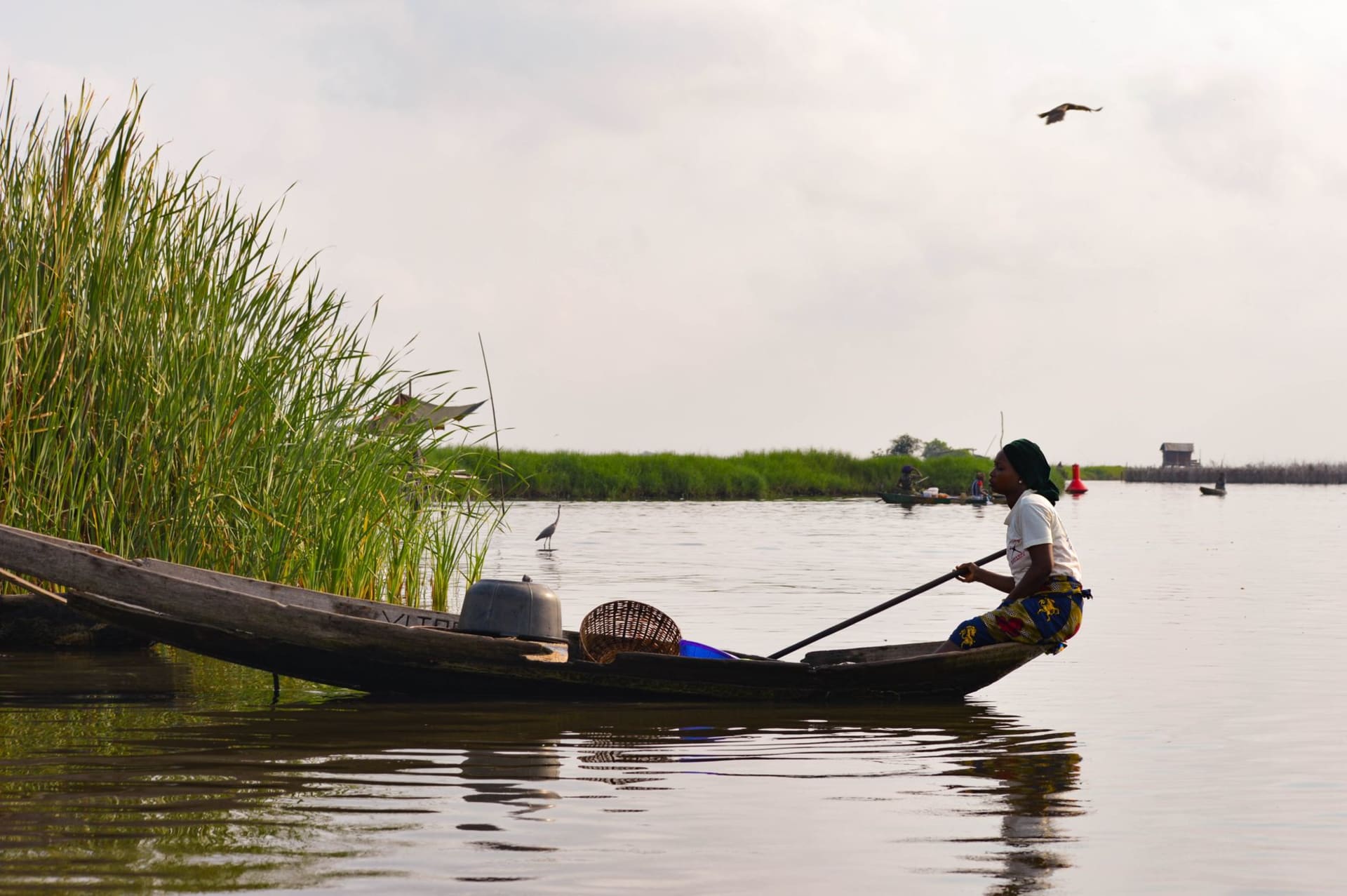 Fishing pirogue silhouetted against the red and gold Atlantic sunset at Grand-Popo, the lagoon glassy behind it