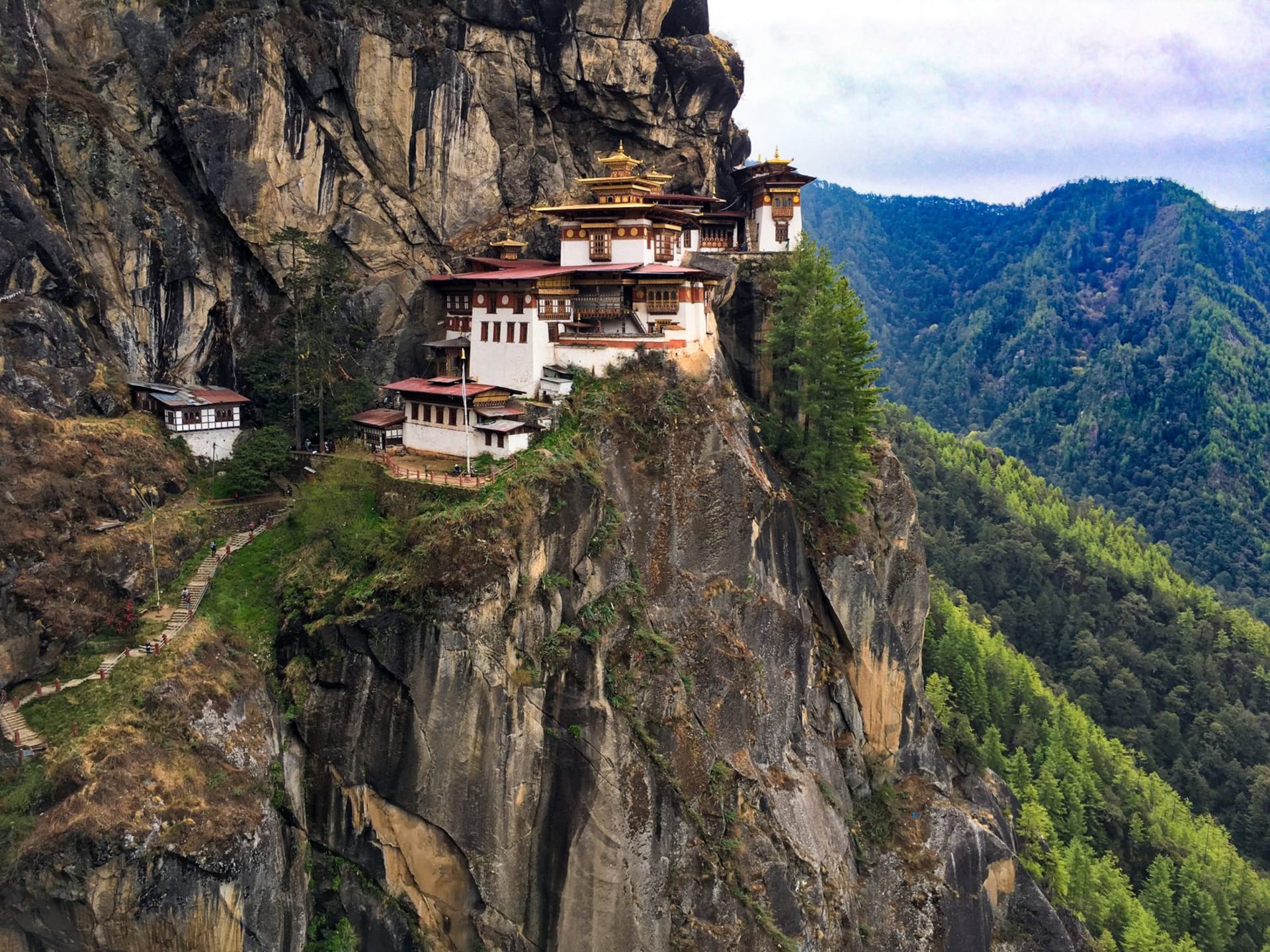 Tiger's Nest Monastery perched on a sheer cliff above a pine forest in Bhutan, photo by Peng Lim