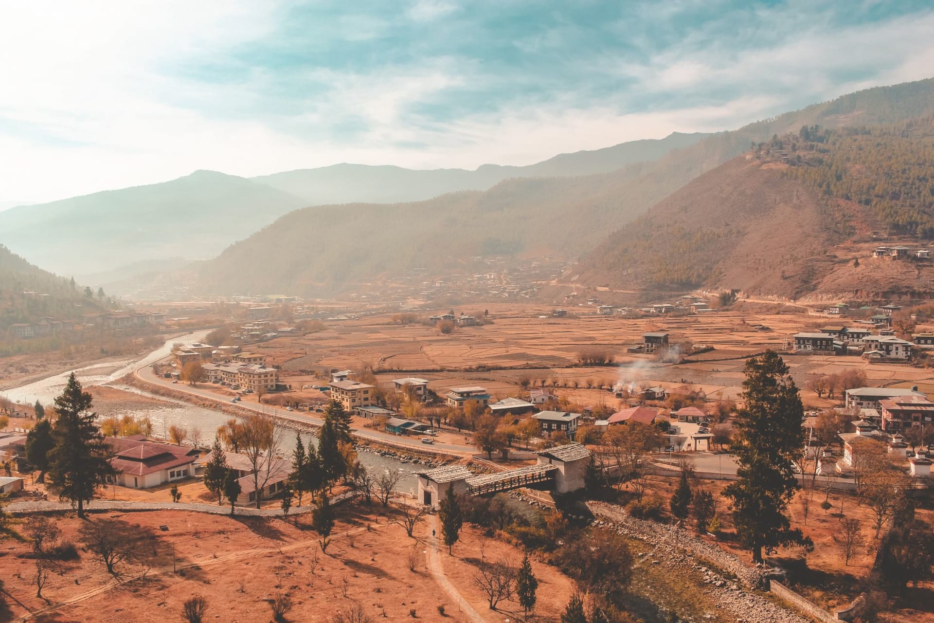 The white Lhakhang Karpo temple in the wide green Haa valley with forested mountains rising on all sides