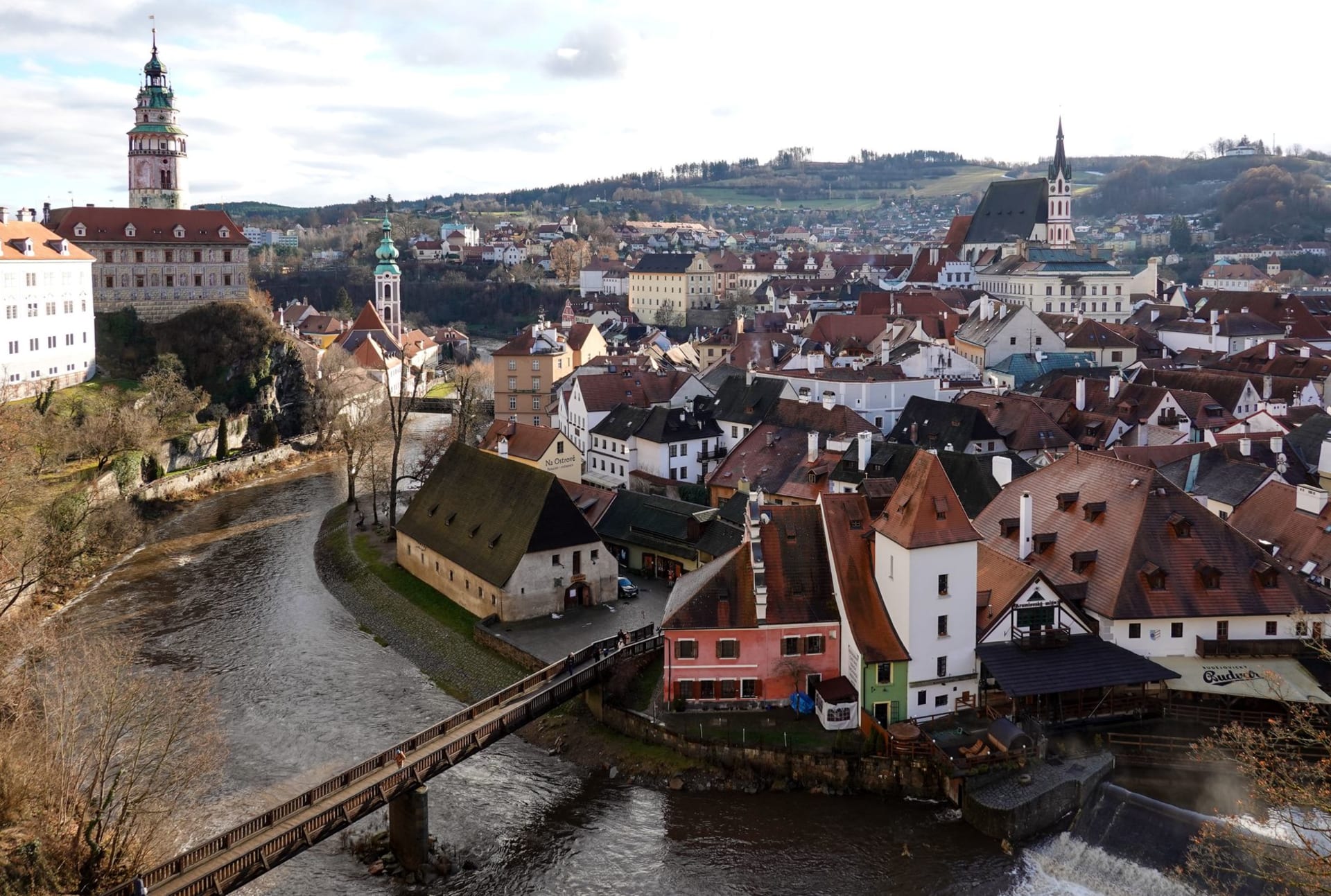 Český Krumlov Castle and its baroque tower rising above terracotta rooftops, with the Vltava River looping around the old town on a clear autumn morning