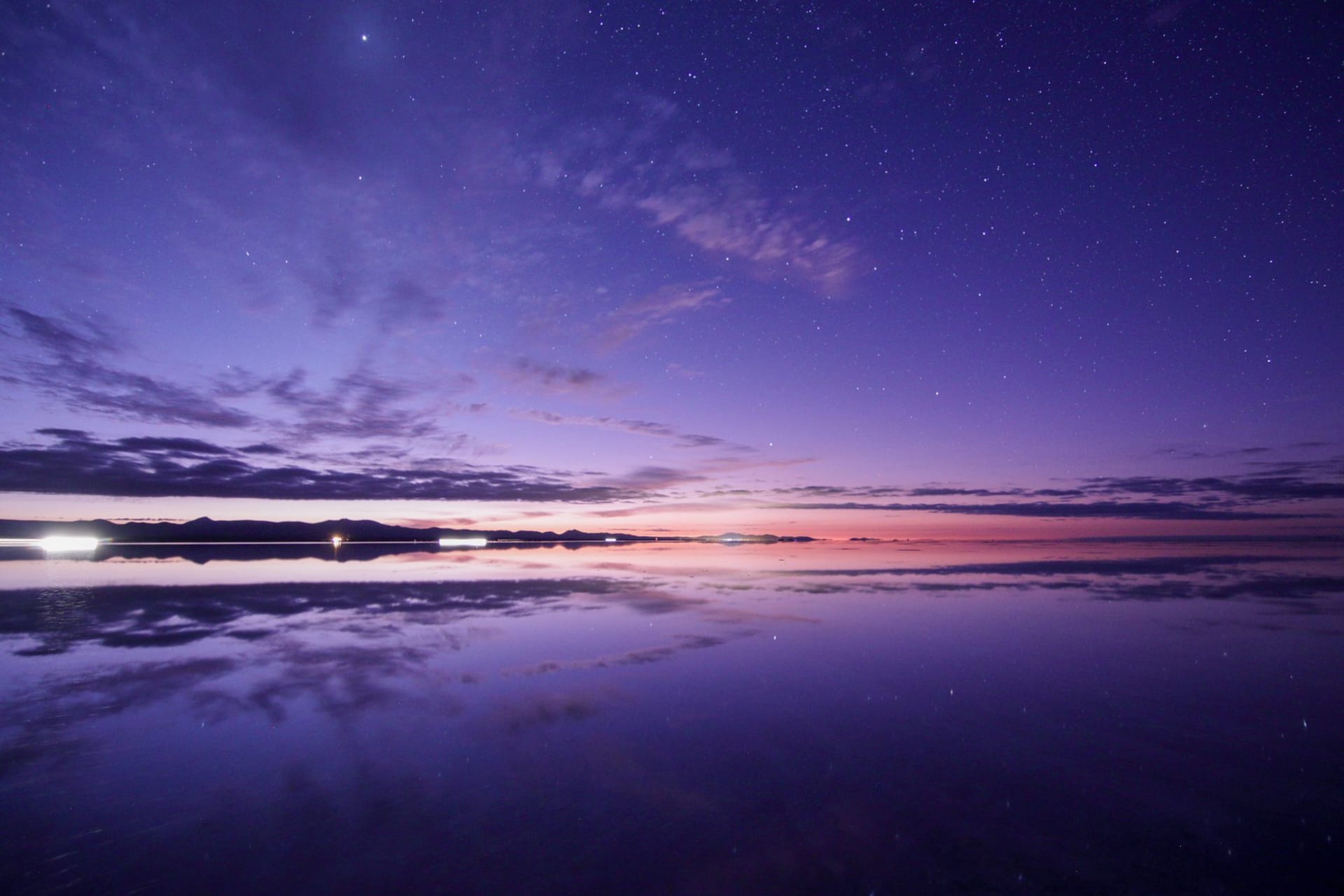 Cielo al atardecer reflejado en la superficie del Salar de Uyuni en Bolivia, duplicando las nubes y la luz que se desvanece