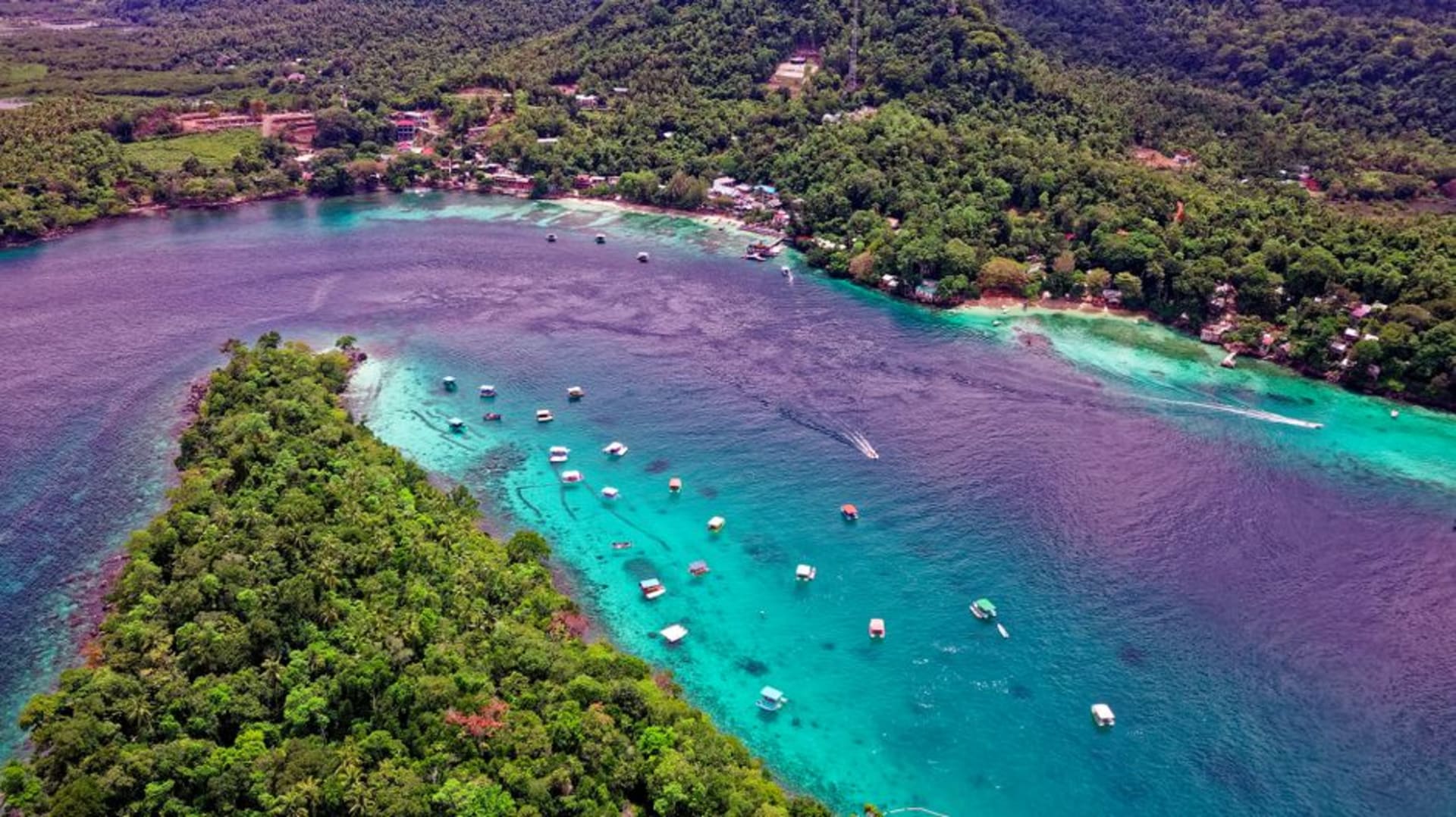 Aguas turquesas y arrecife de coral rodeando una pequeña isla del archipiélago de Derawan
