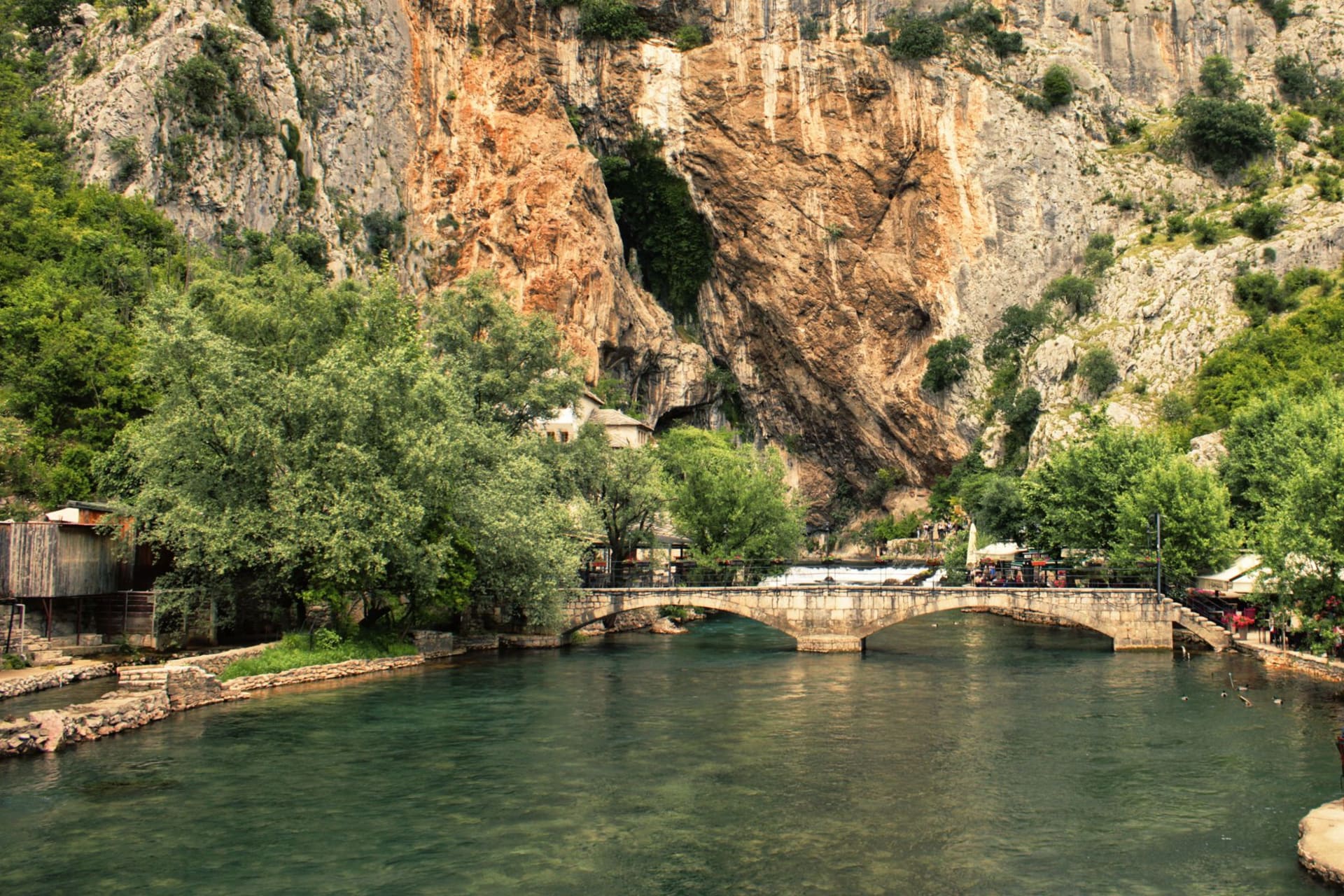 The white-walled Blagaj Tekke monastery nestled at the base of a towering limestone cliff beside the crystal source of the Buna river