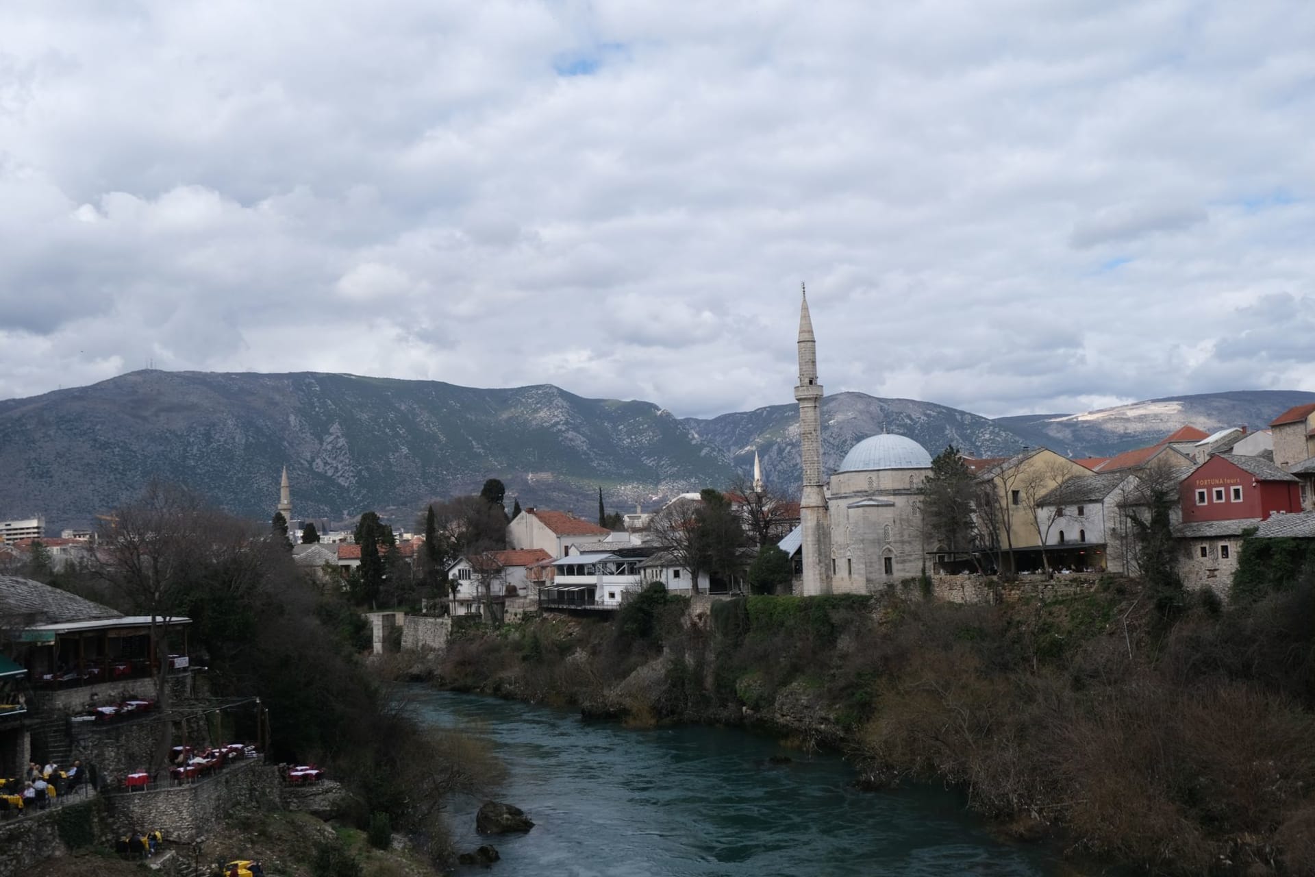 Stari Most bridge arching over the turquoise Neretva river at dawn, the old town's stone towers rising on either bank