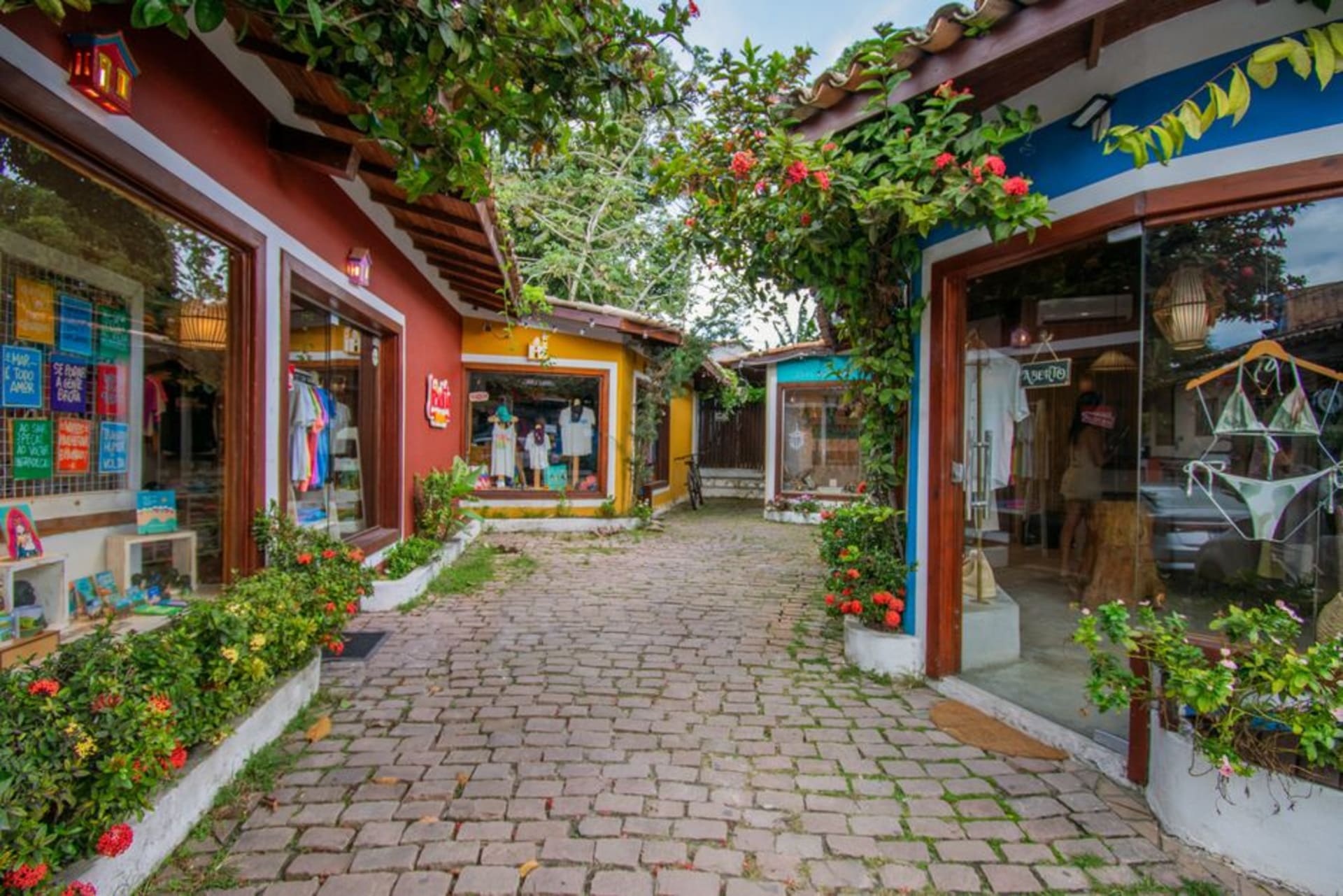 Calle peatonal de arena en Arraial d'Ajuda bordeada de bares y puestos de artesanías al atardecer