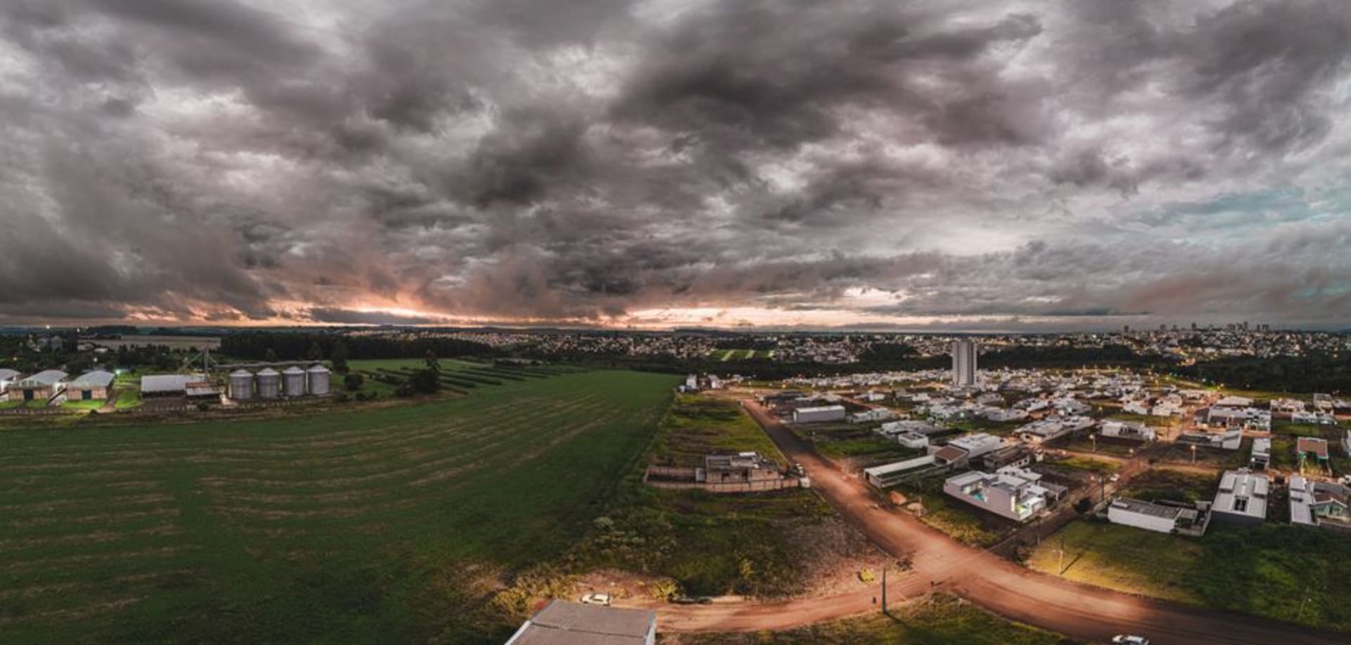 Large avenue bordée d'arbres à Campo Grande, avec la terre rouge visible sur les bas-côtés