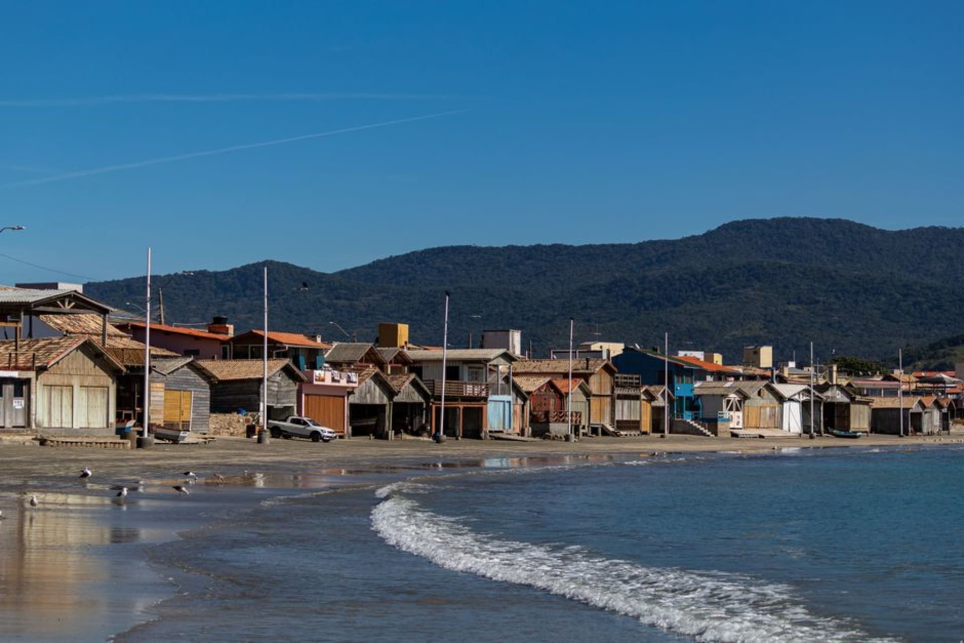 Fishing boats pulled up on the sand at Garopaba's main beach with green hills rising behind the town