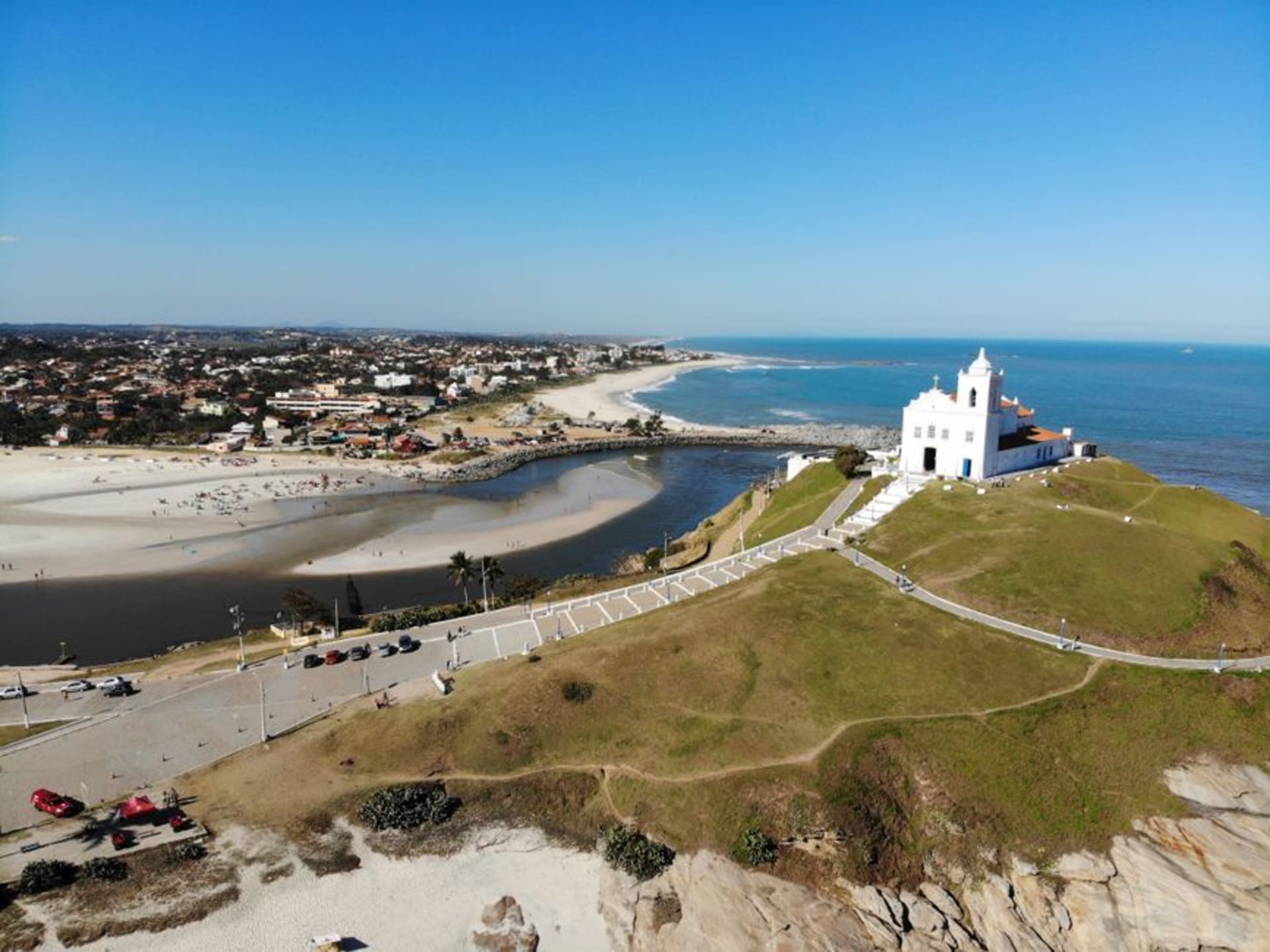 Waves breaking at Praia de Itauna in Saquarema with the hilltop chapel of Nossa Senhora de Nazare above the point