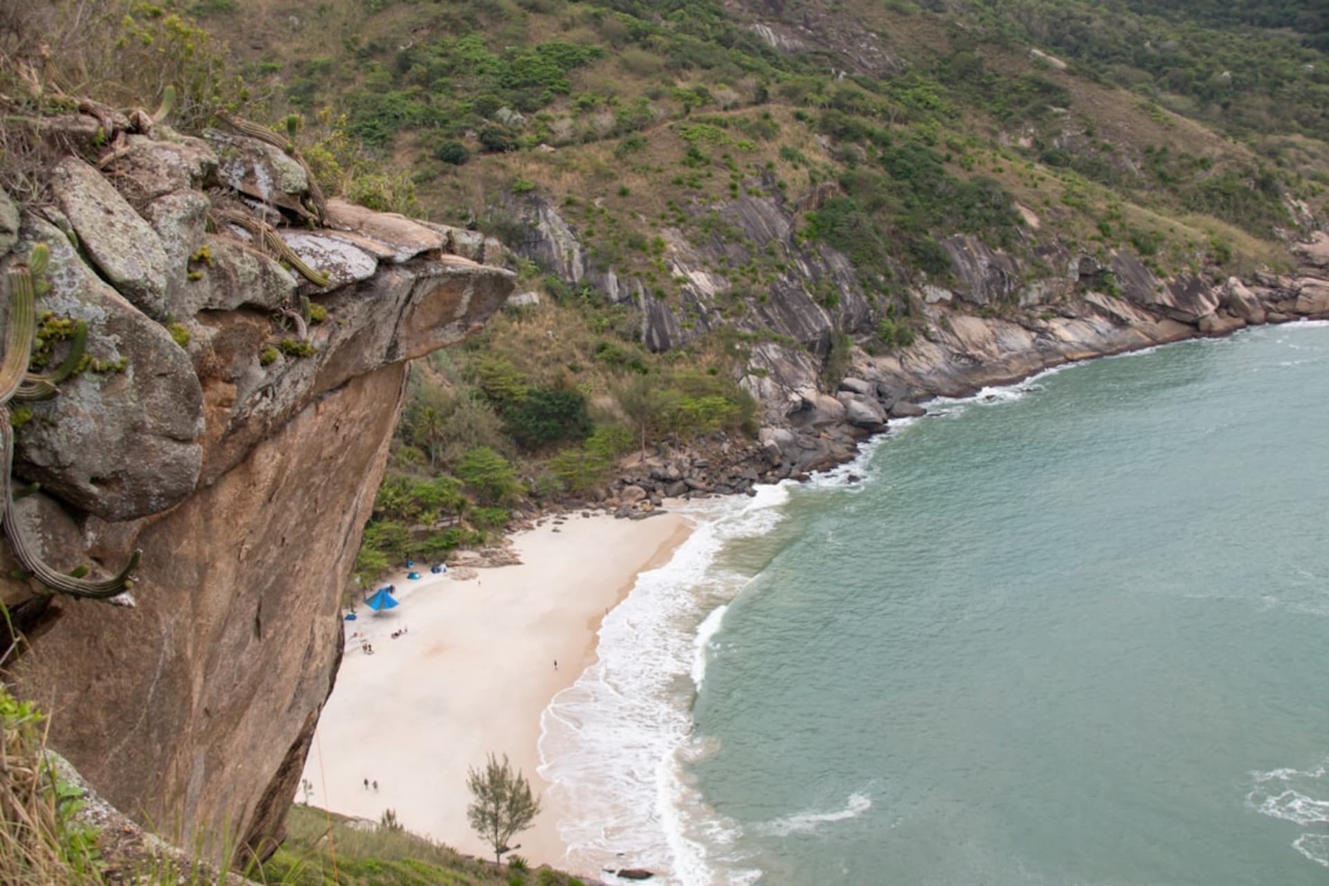 Playa de arena curvada en Ubatuba enmarcada por colinas boscosas y oleaje tranquilo