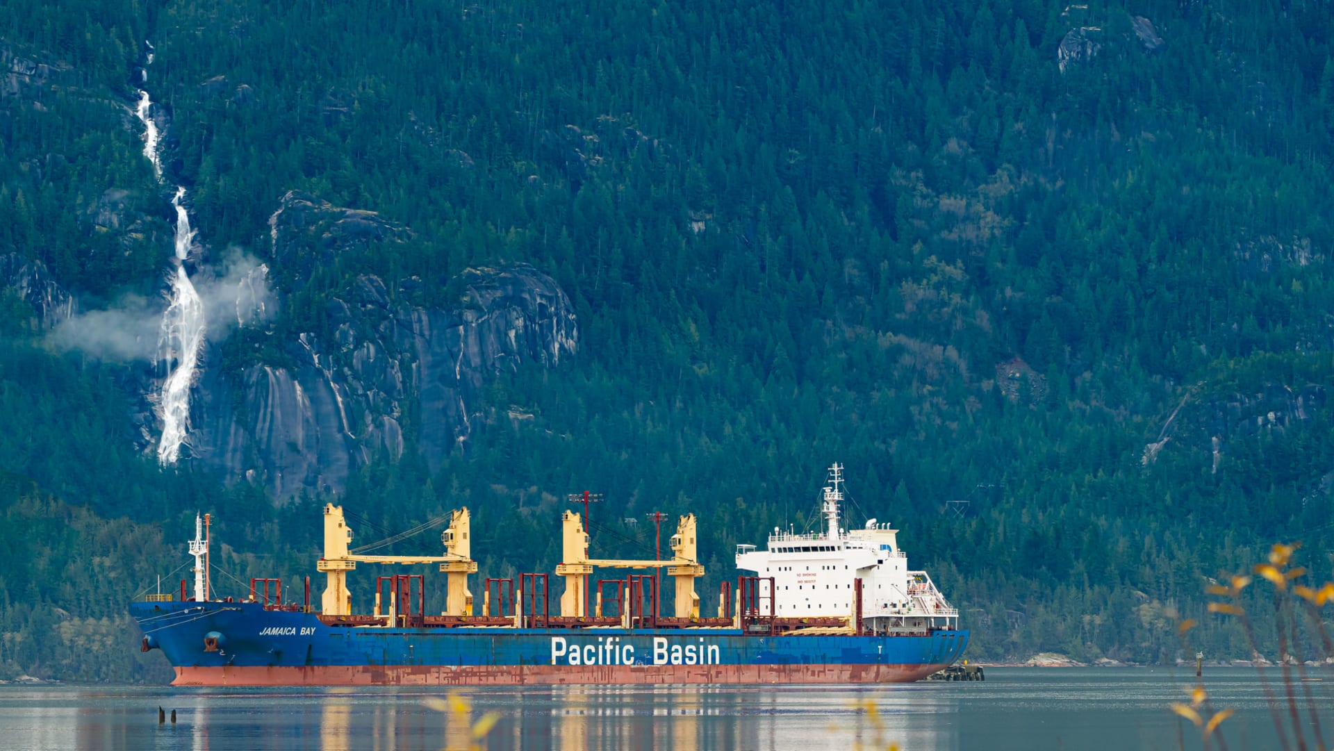 El monolito de granito del Stawamus Chief elevándose sobre el bosque de abeto Douglas cerca de Squamish, con el agua azul del Howe Sound visible en el valle abajo
