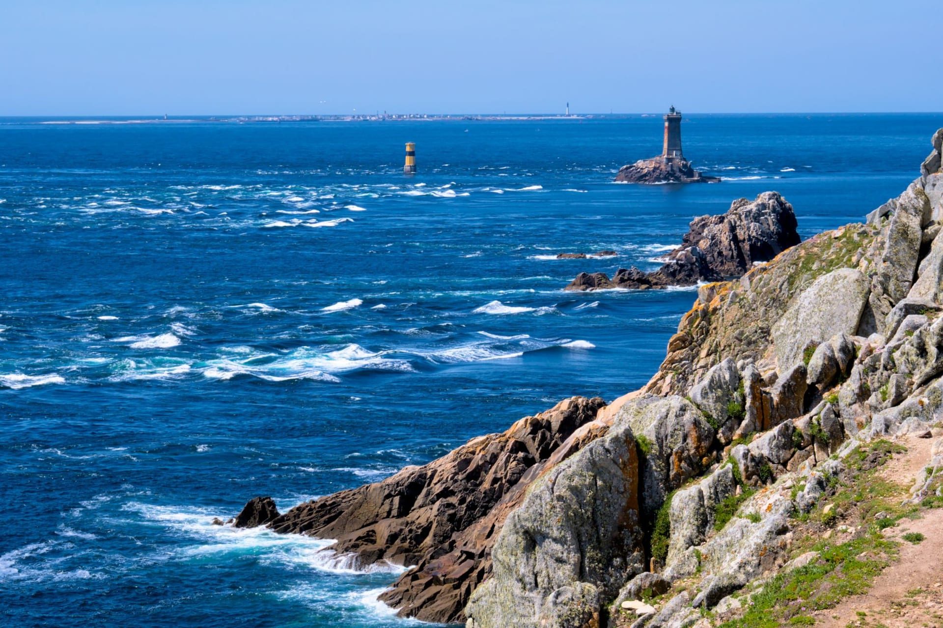 Rocky cliffs and twin lighthouses at Plogoff on the Brittany coast, France, under a dramatic Atlantic sky