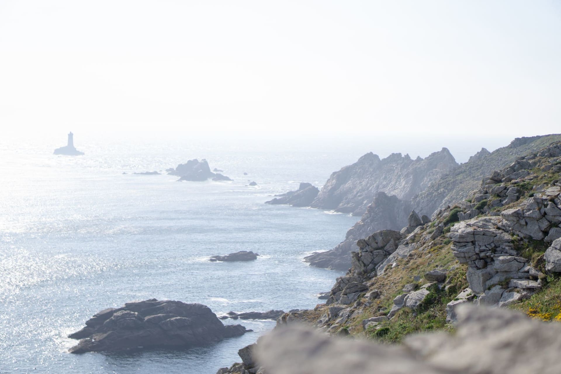 The jagged schist headland of Pointe du Raz jutting into the Atlantic Ocean under a storm-lit sky, Finistère