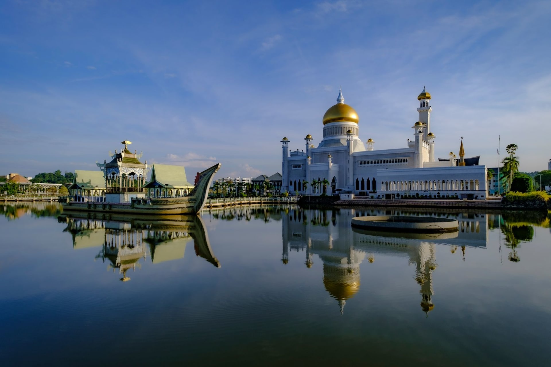 Omar Ali Saifuddien Mosque reflected in the calm lagoon at sunrise, its golden dome glowing against the pale sky in Bandar Seri Begawan
