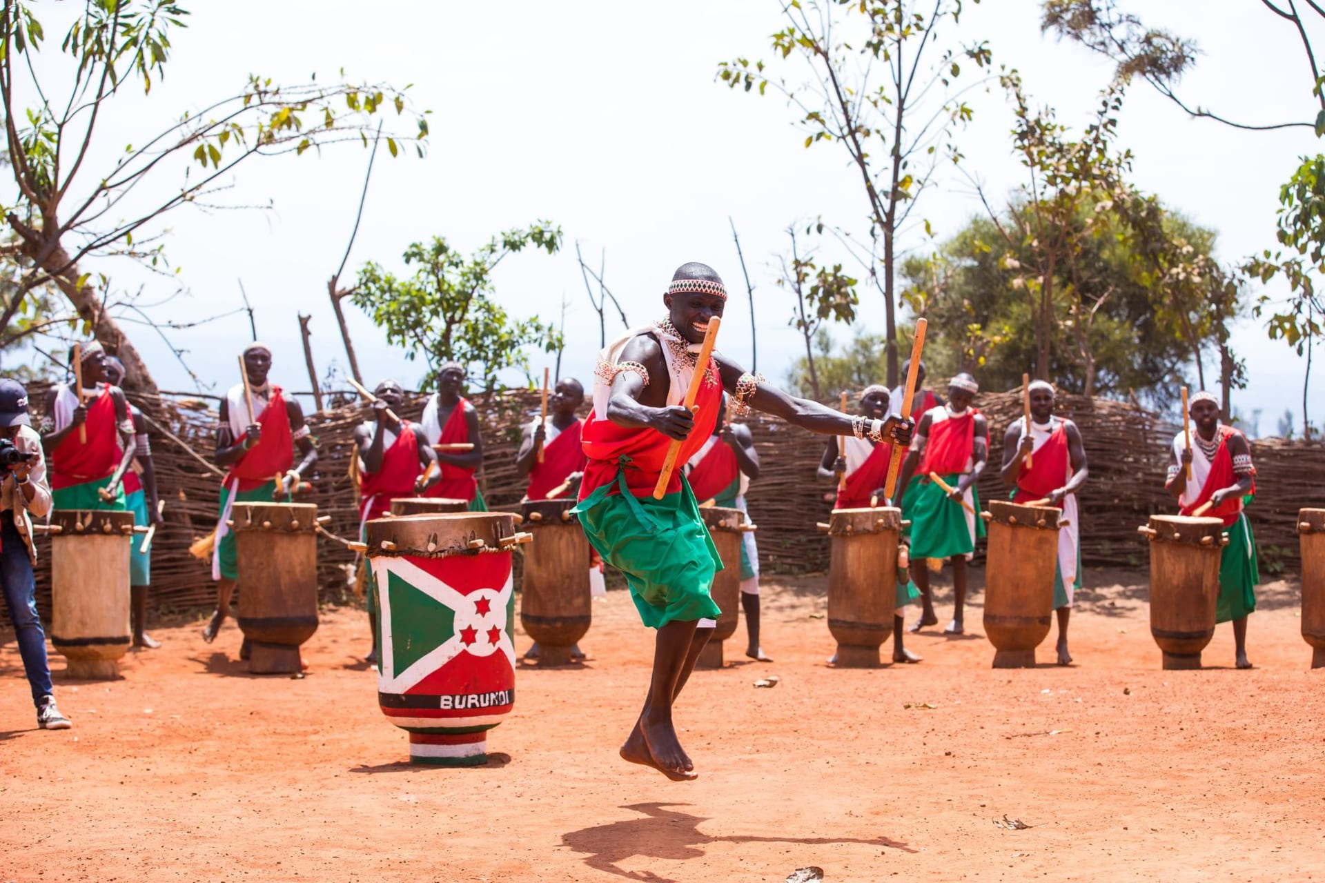 Rolling green hills of Gitega with a mist-wrapped highland town and red clay roads winding between terraced farms