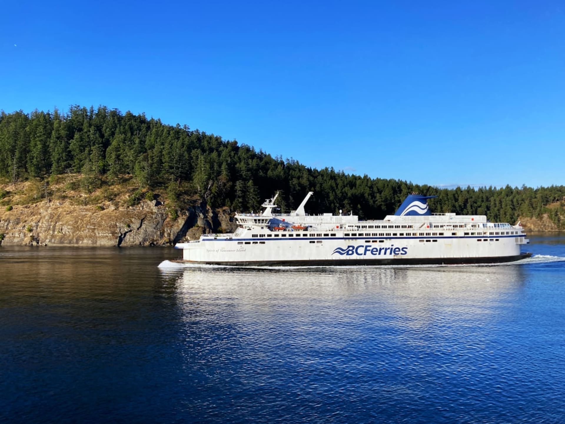 Ferry crossing calm waters of the Gulf Islands with forested islets and arbutus trees along the shoreline