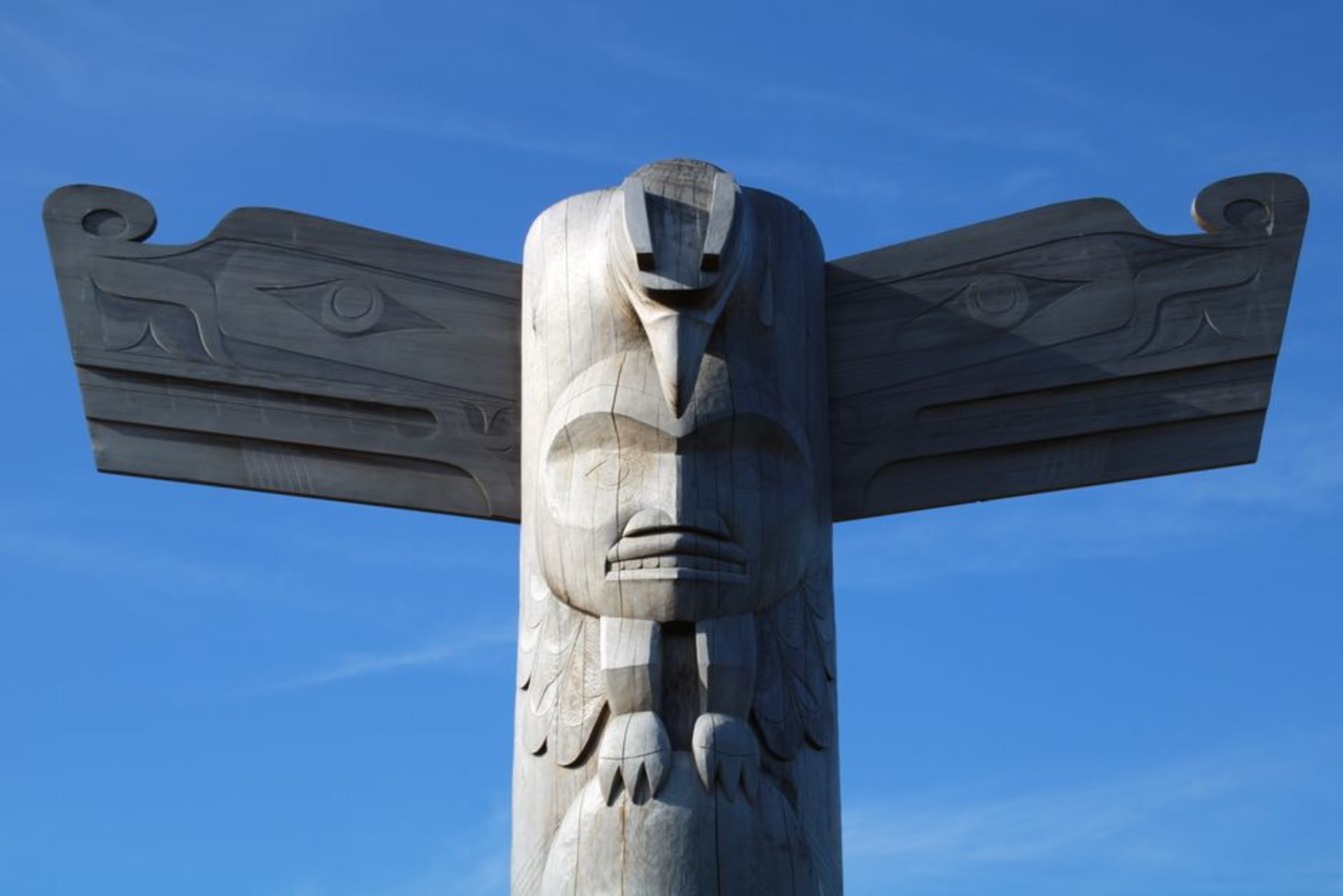 Carved Haida totem poles standing before a misty rainforest shoreline