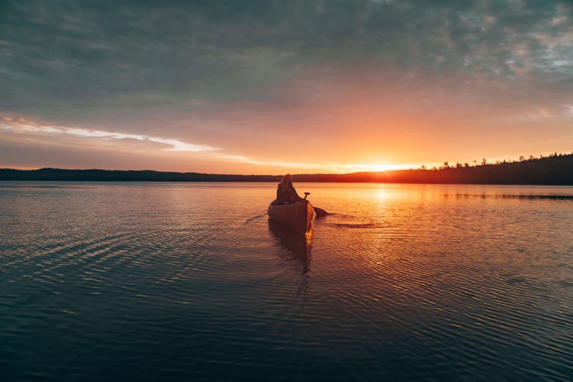 Canoe resting on a still Haliburton lake at sunrise with mist rising off the water