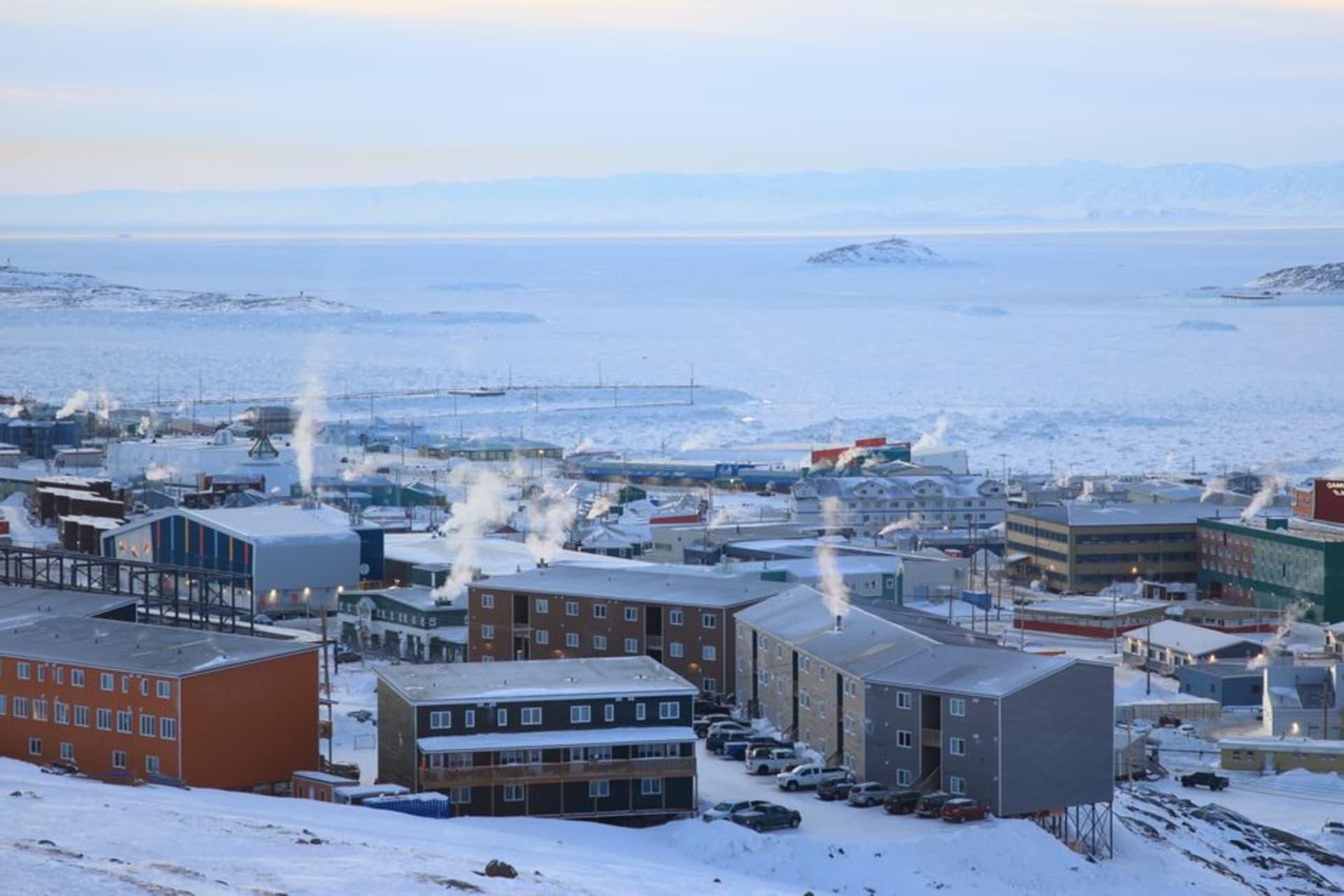 Brightly painted houses of Iqaluit set against open tundra and grey Frobisher Bay water