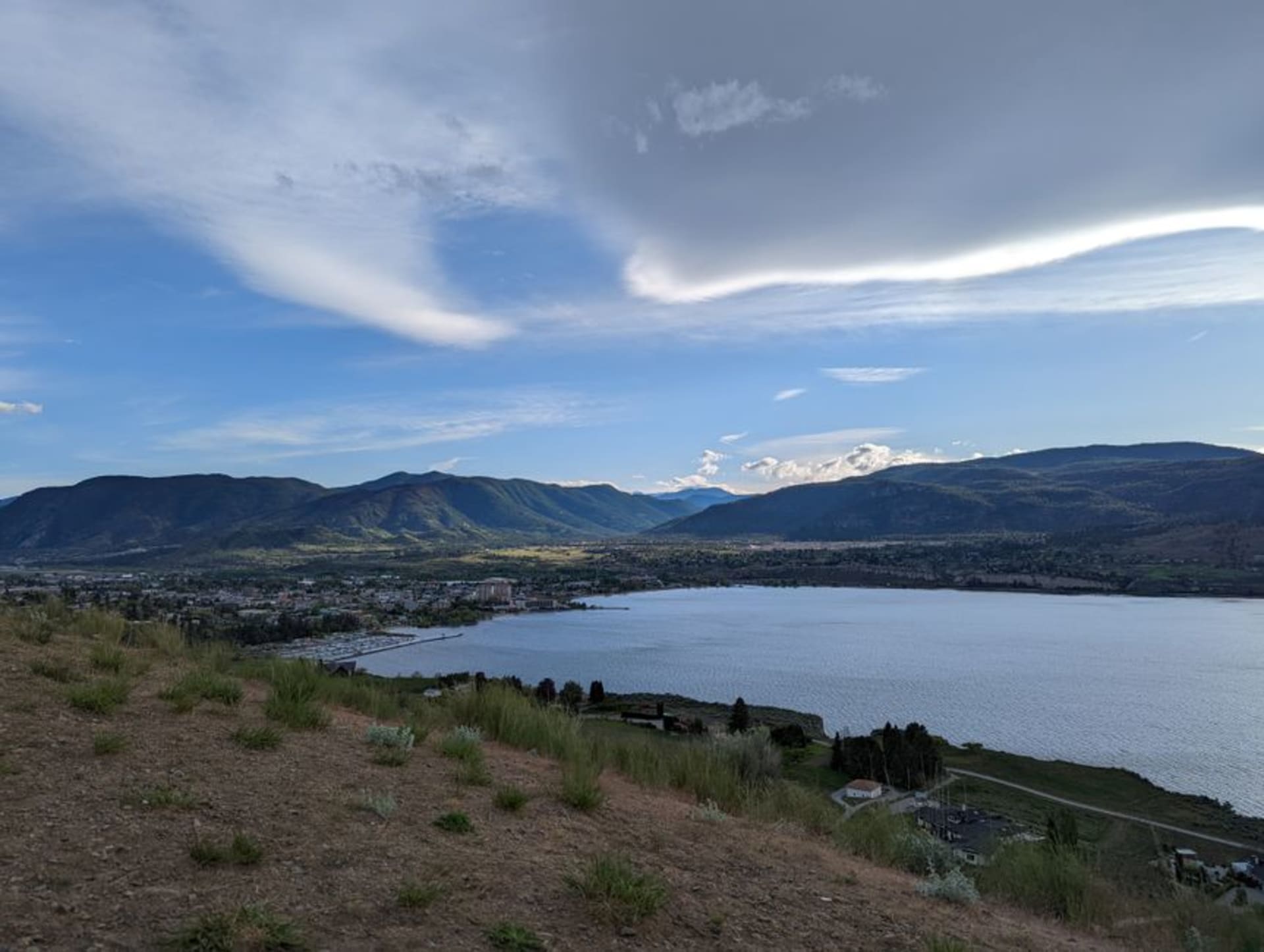 Vineyard rows overlooking Okanagan Lake under a hot summer sky