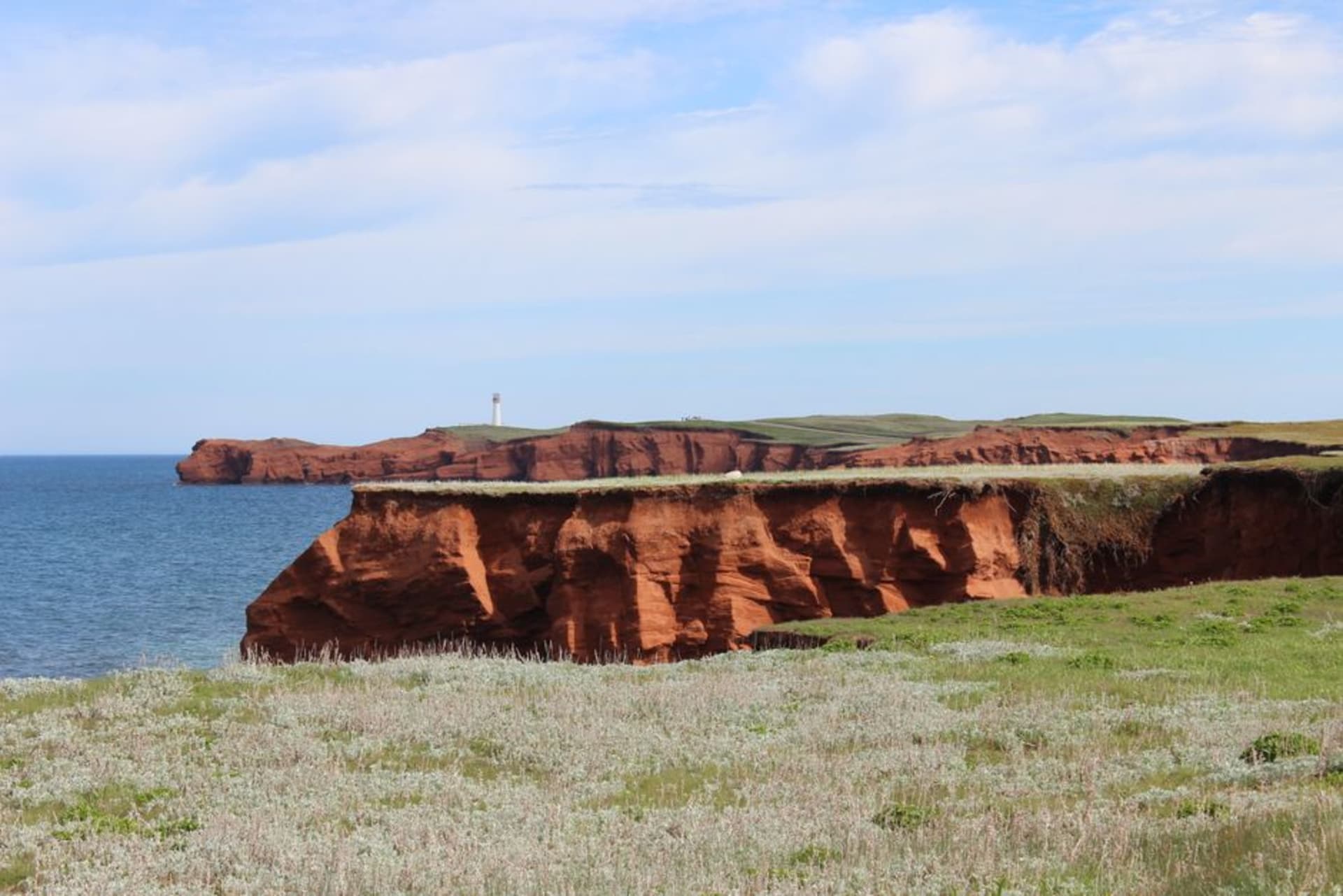 Red sandstone cliffs rising above turquoise water on a Magdalen Islands coastline