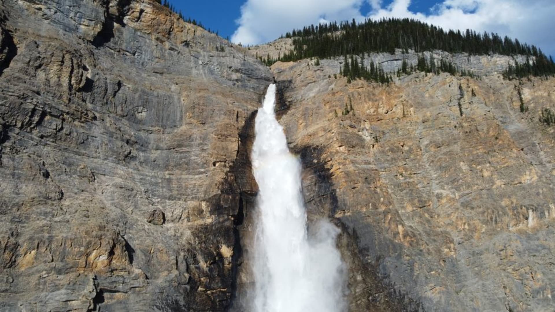 Takakkaw Falls cascading down a sheer cliff face in Yoho National Park with mist rising at the base