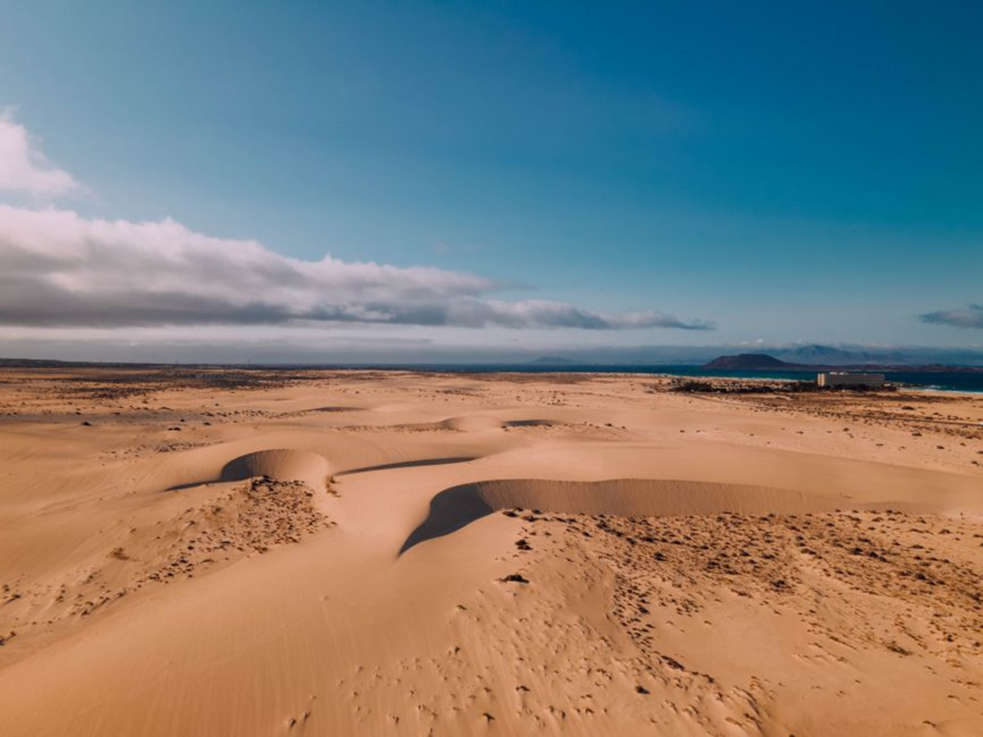 Golden sand dunes of Corralejo Natural Park meeting the turquoise Atlantic in Fuerteventura