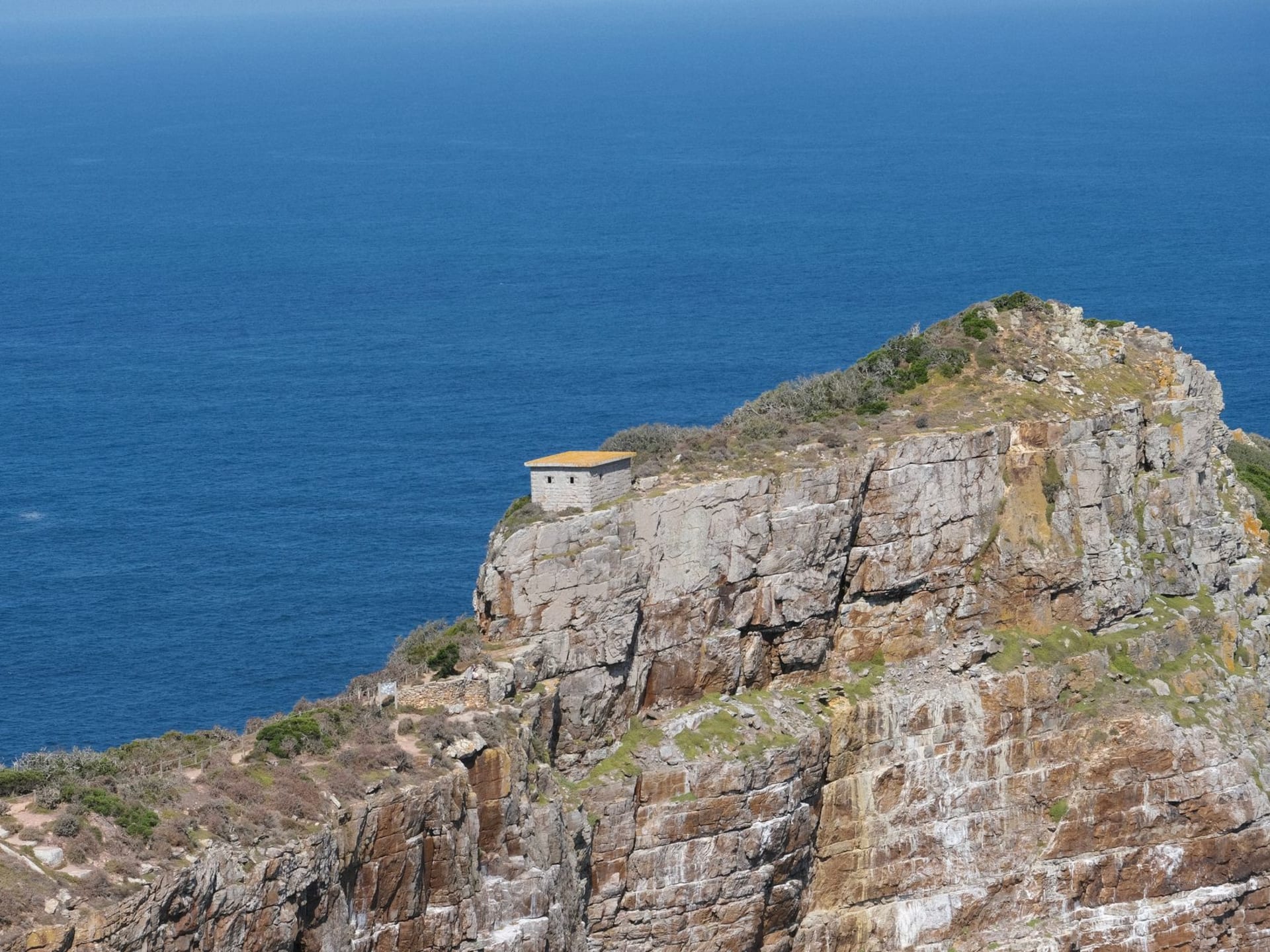 Rocky cliffs of the Cape Peninsula rising above a deep blue Atlantic sea under a dramatic sky