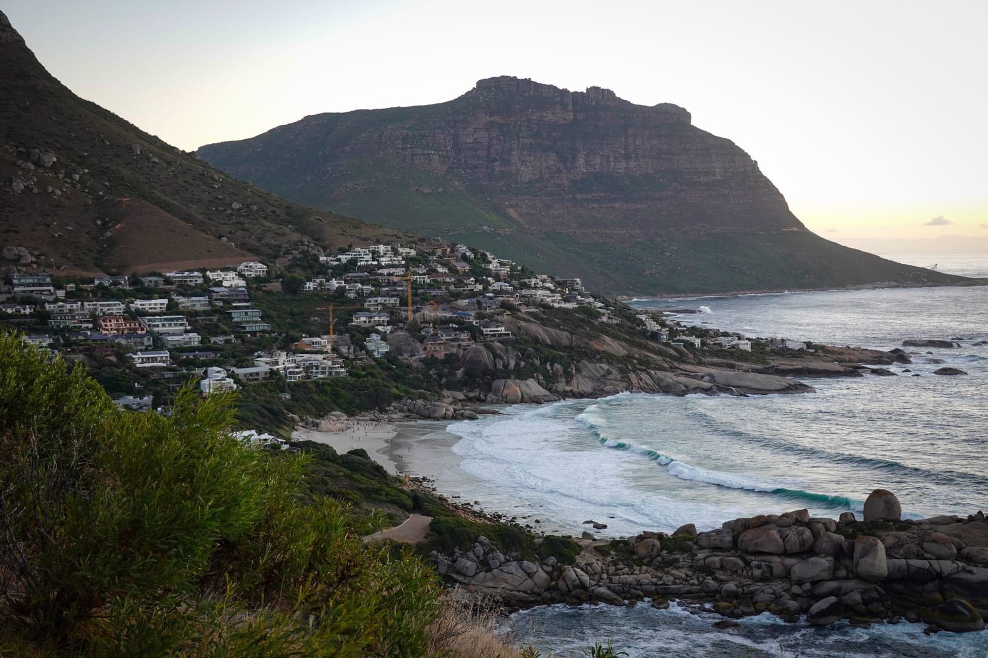 Hout Bay harbor with working trawlers docked and the dramatic mountains of the Cape Peninsula enclosing the bay on three sides