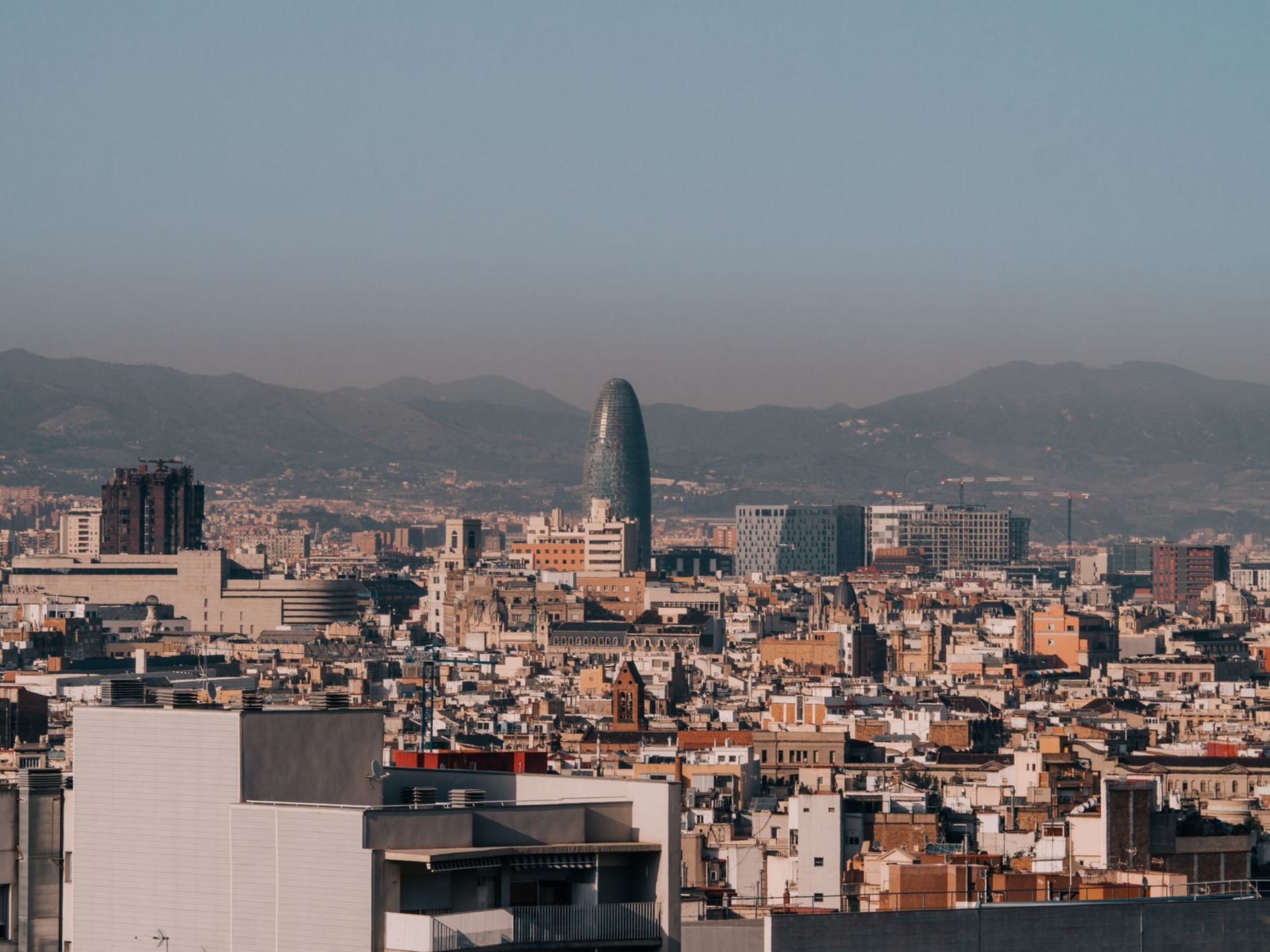 The spires of Sagrada Família rising above Barcelona's rooftops in morning golden light