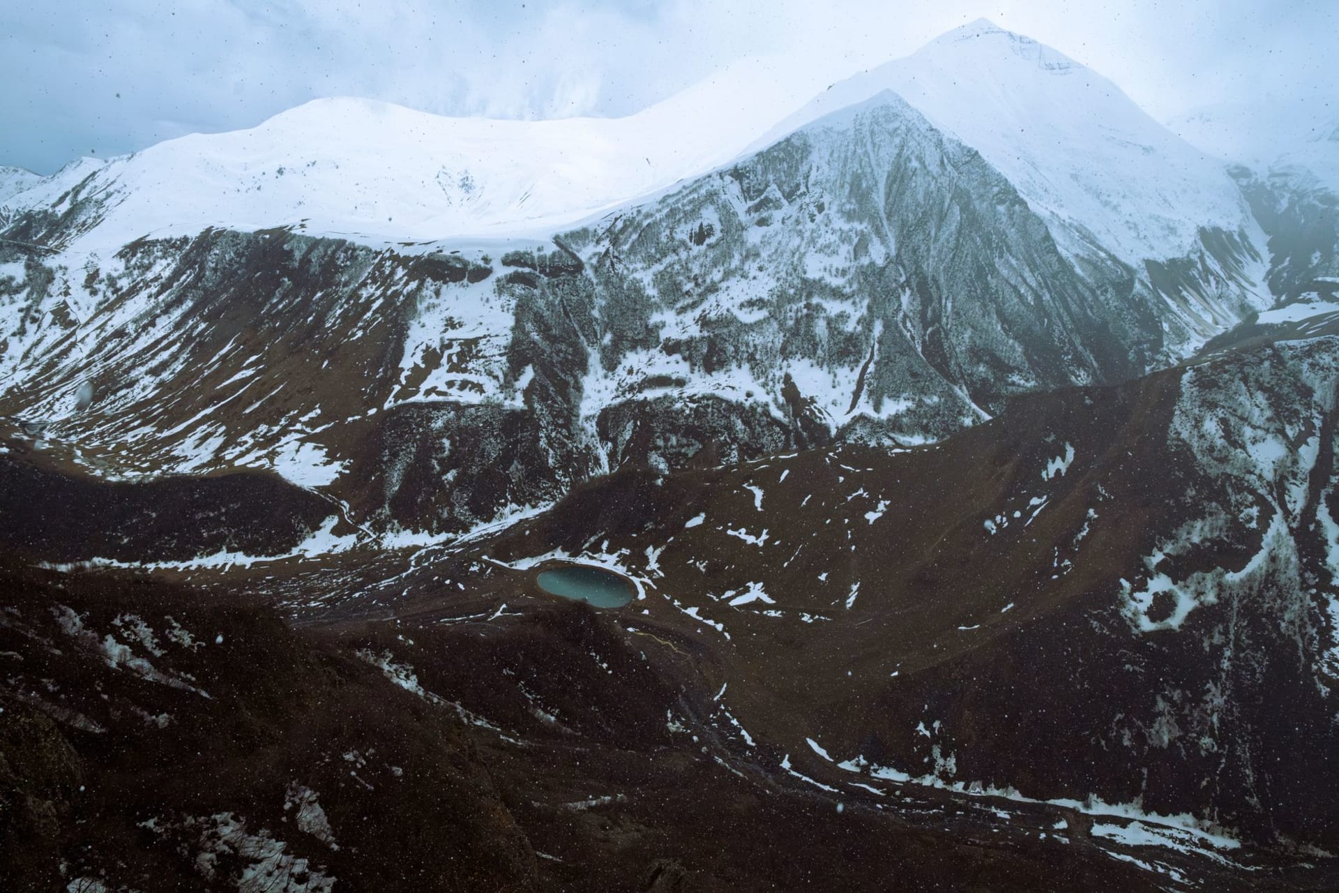 Khinalig village cascading down a rocky mountainside above 2,200 meters, stone houses stacked against each other with endless Caucasus ridges behind