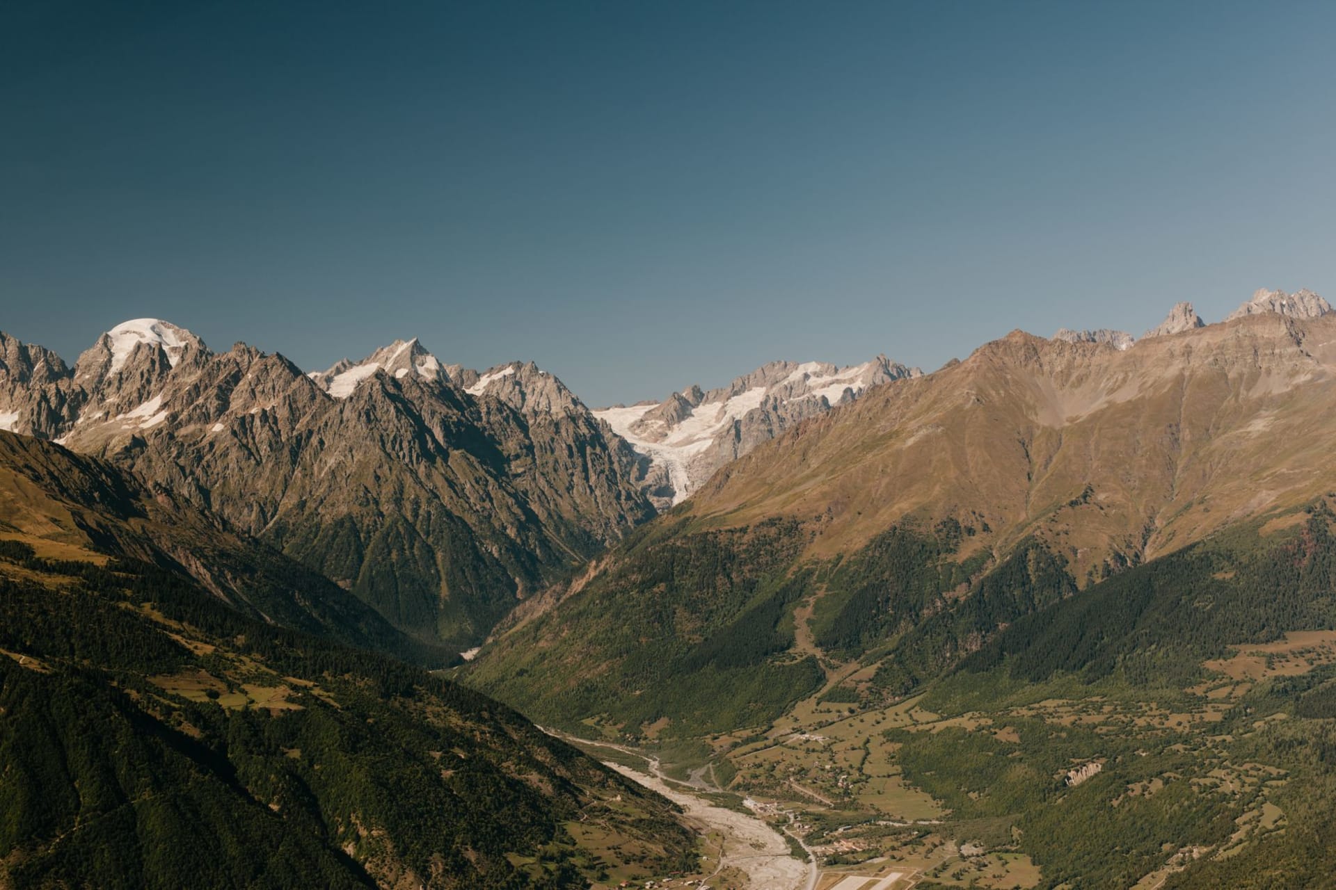 Cluster of medieval Svan towers rising above slate-roofed houses with Shkhara glacier in the background