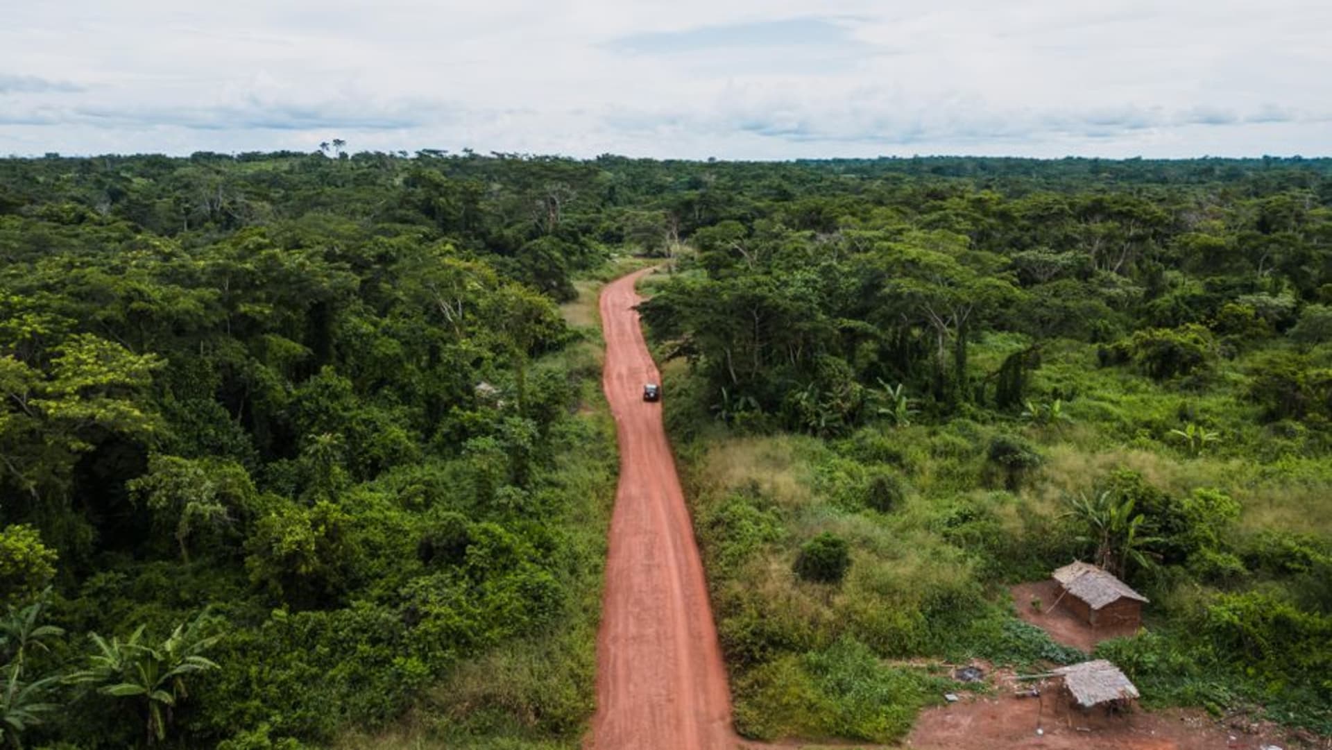 A red laterite border crossing road lined with forest at Gamboula on the frontier between Central African Republic and Cameroon