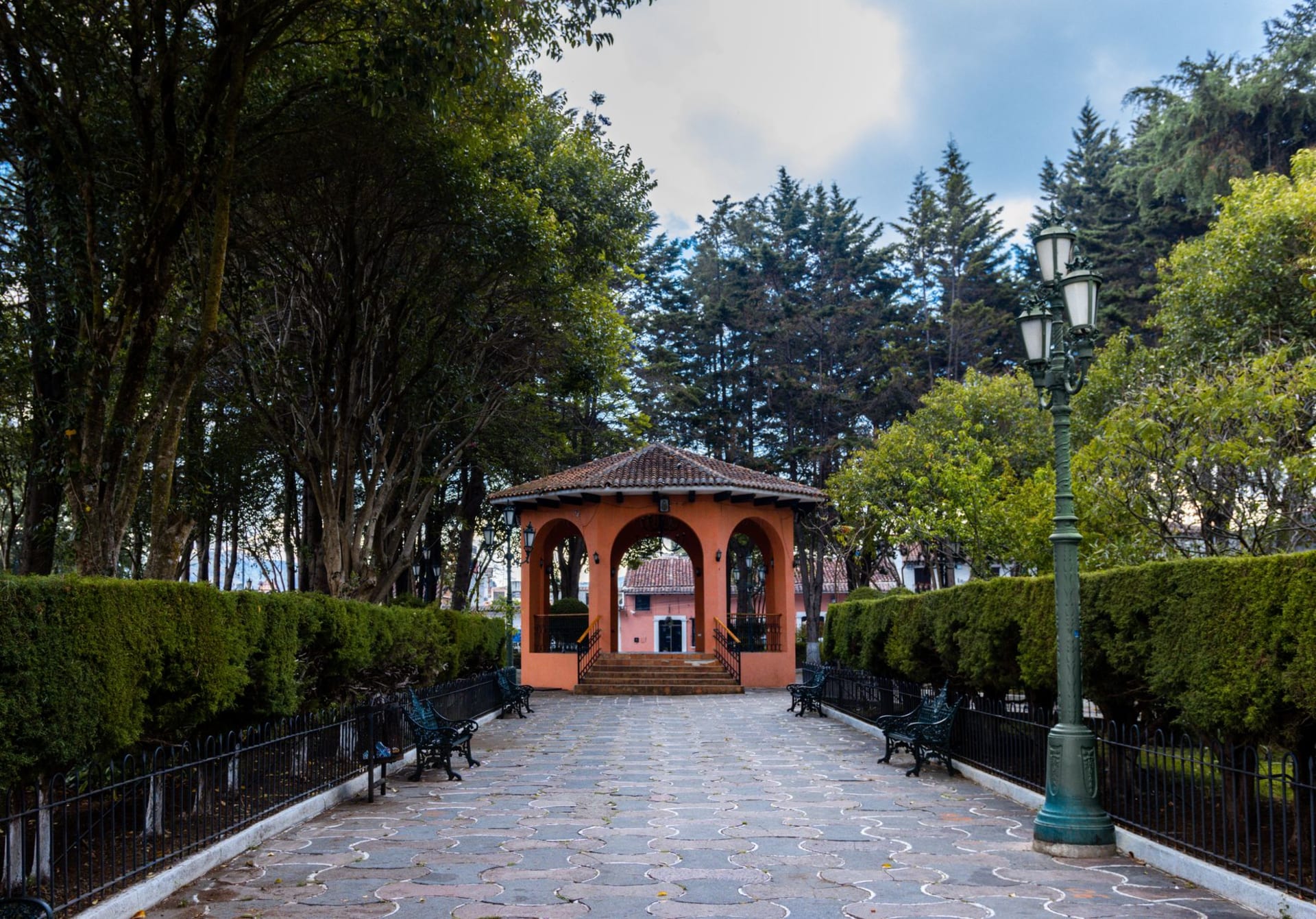 Comitán de Domínguez's arcaded central plaza with colonial church tower and mountains in the background at dusk