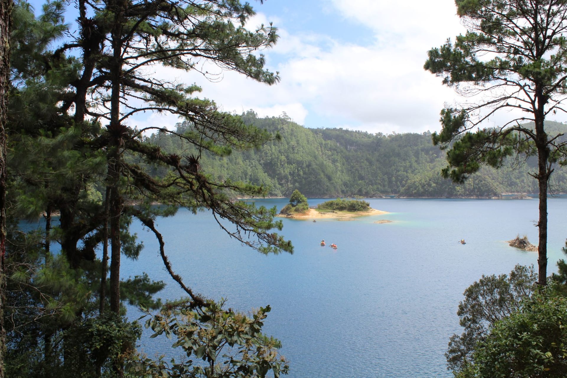 Un lago índigo profundo en Lagos de Montebello rodeado de pinos con las highlands de Guatemala visibles a lo lejos