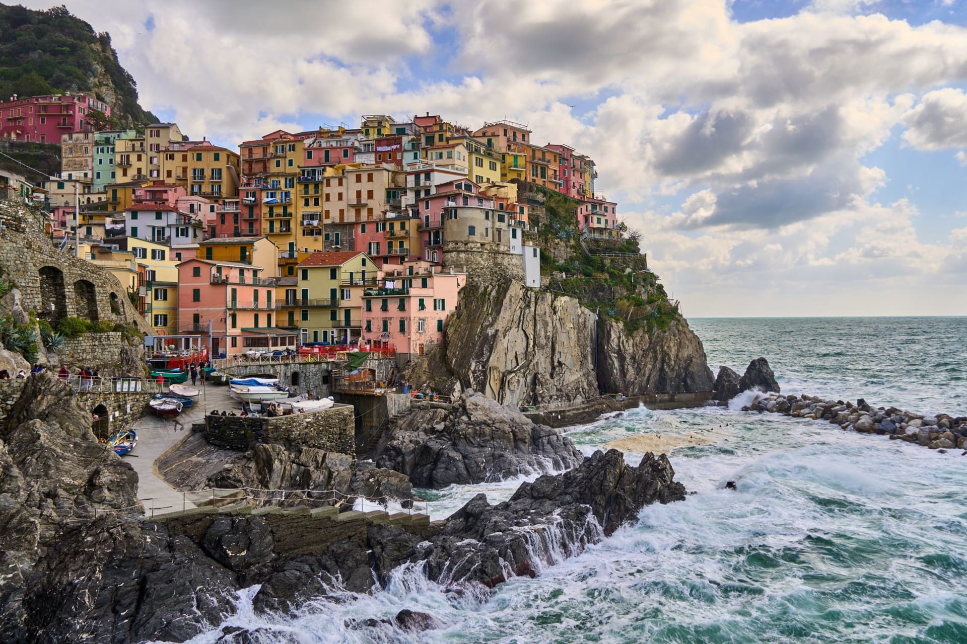 Manarola's multicolored tower houses reflected in the dark water of the inlet at golden hour